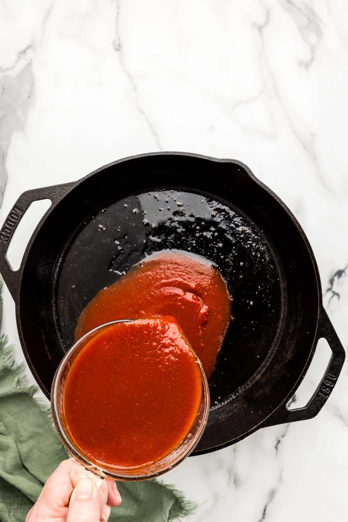 Sauce being poured into a cast iron skillet.