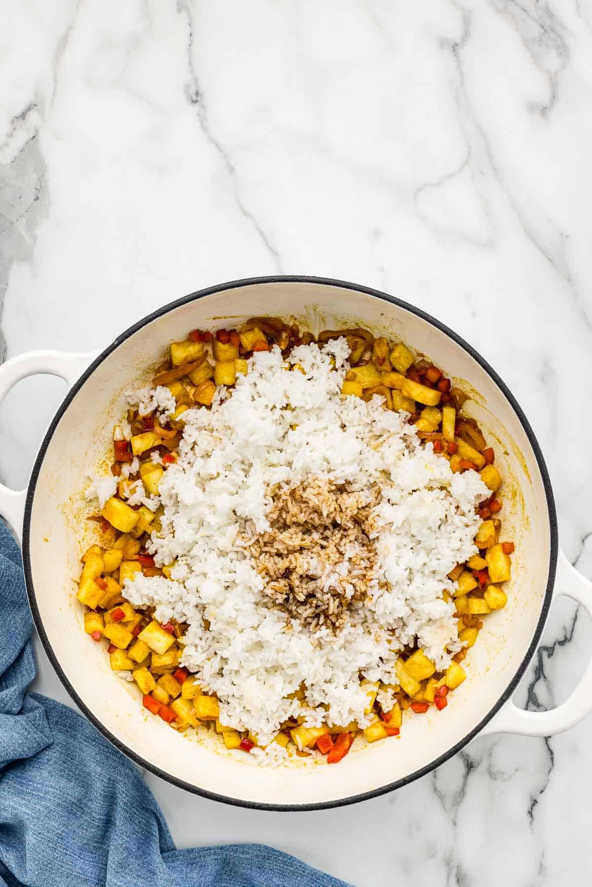 Rice added to a skillet of veggies.