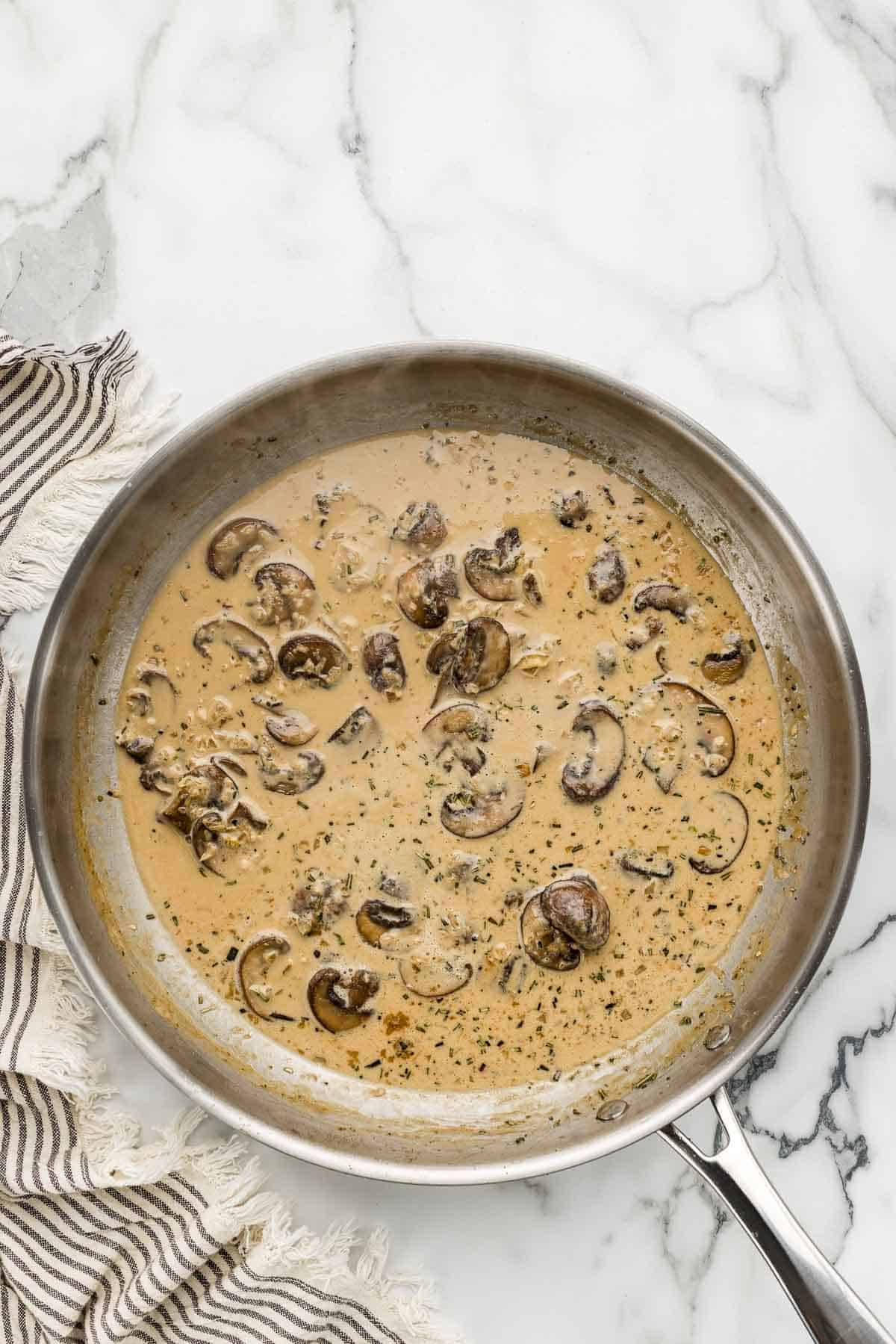 Creamy sauce in a large pan with mushrooms.