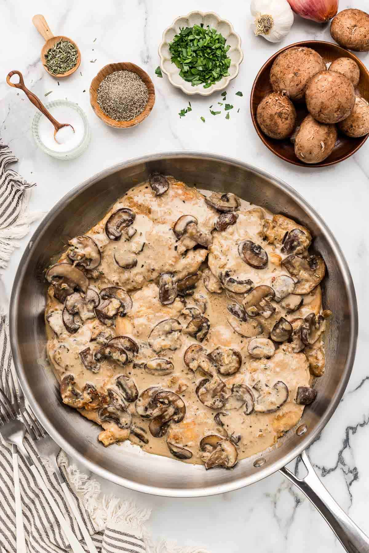 A pan of chicken marsala with small dishes of ingredients above it.