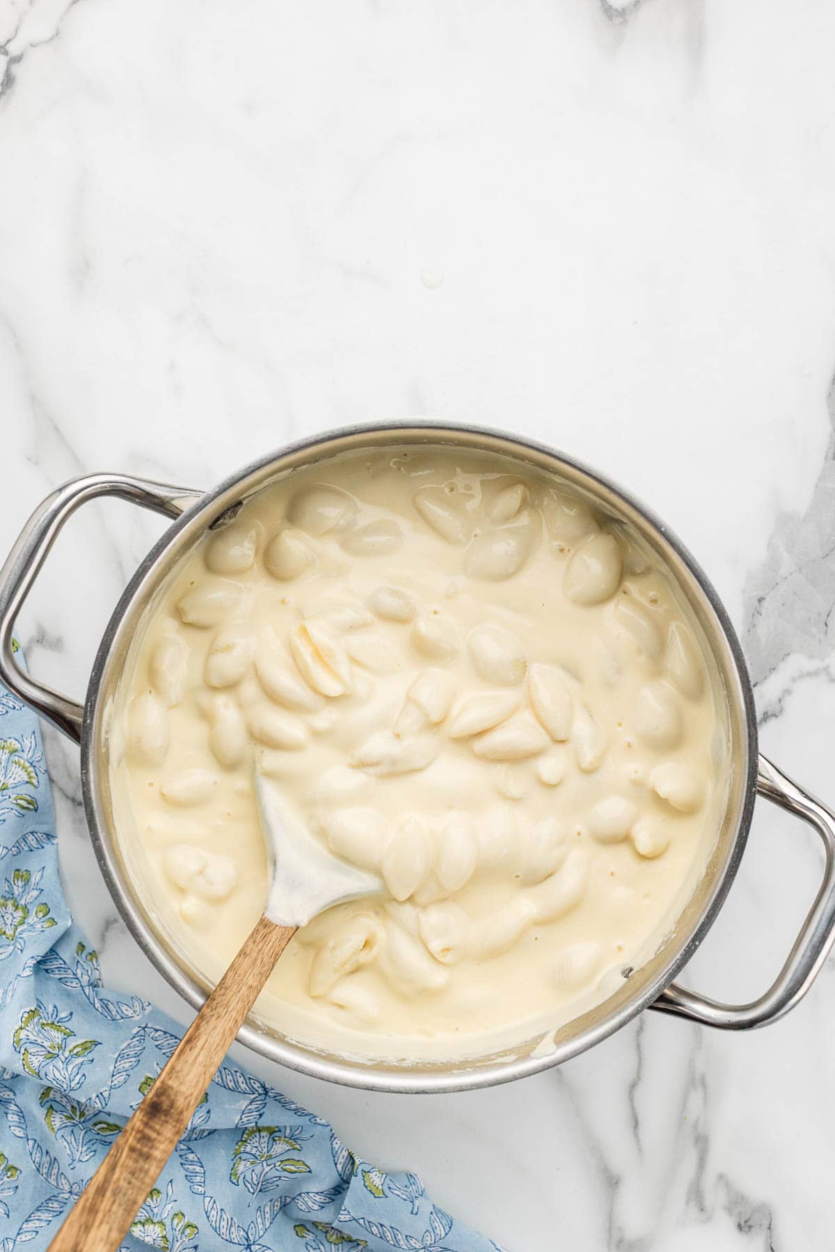 Noodles and cheese sauce mixed in a pot with a cooking spoon.