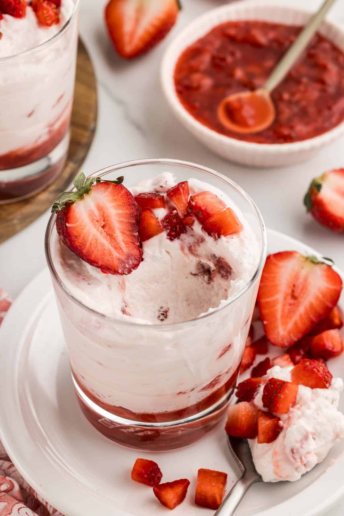 A glass of strawberry mousse with a bite taken out of the top.