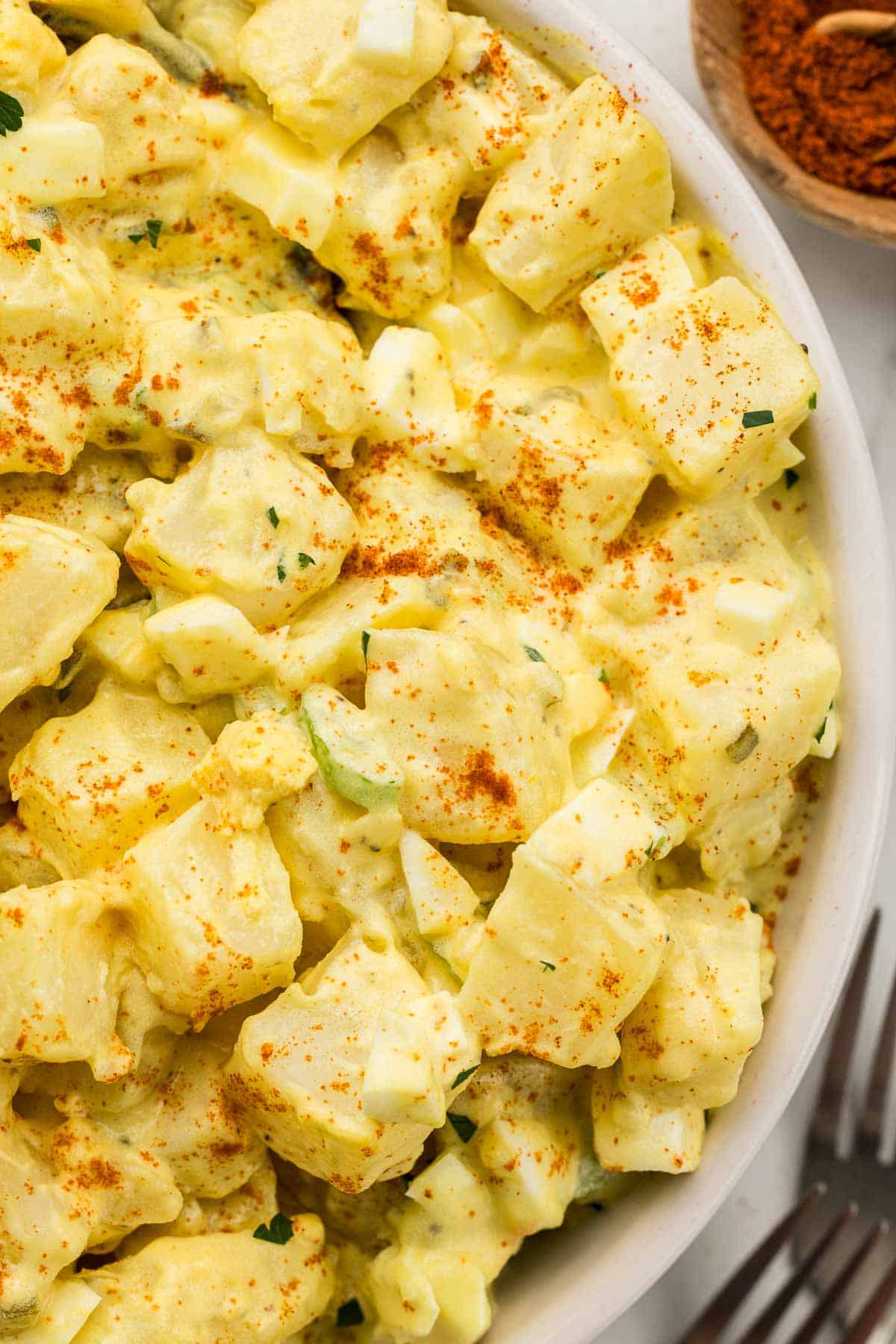 Closeup of potato salad served in a white bowl.