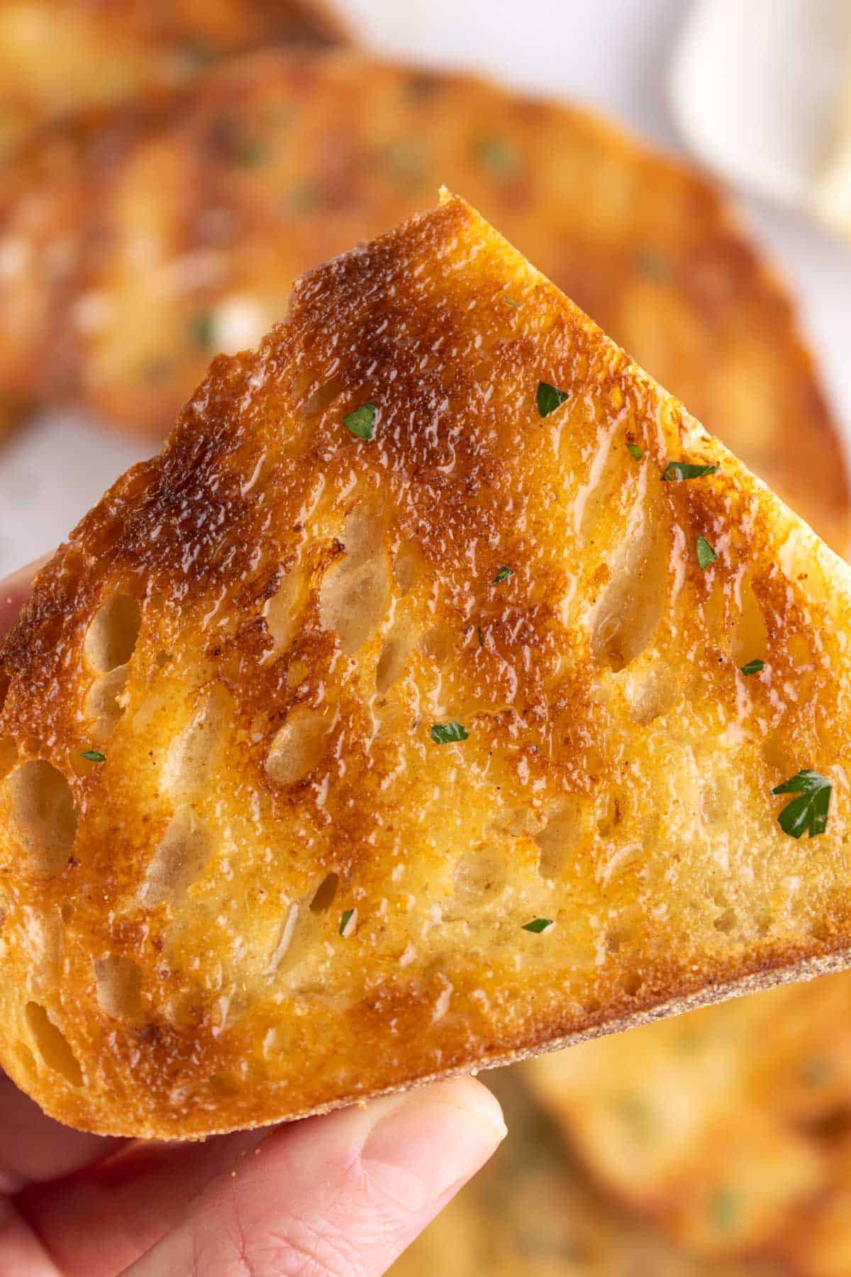 Closeup of a slice of grilled bread being held.