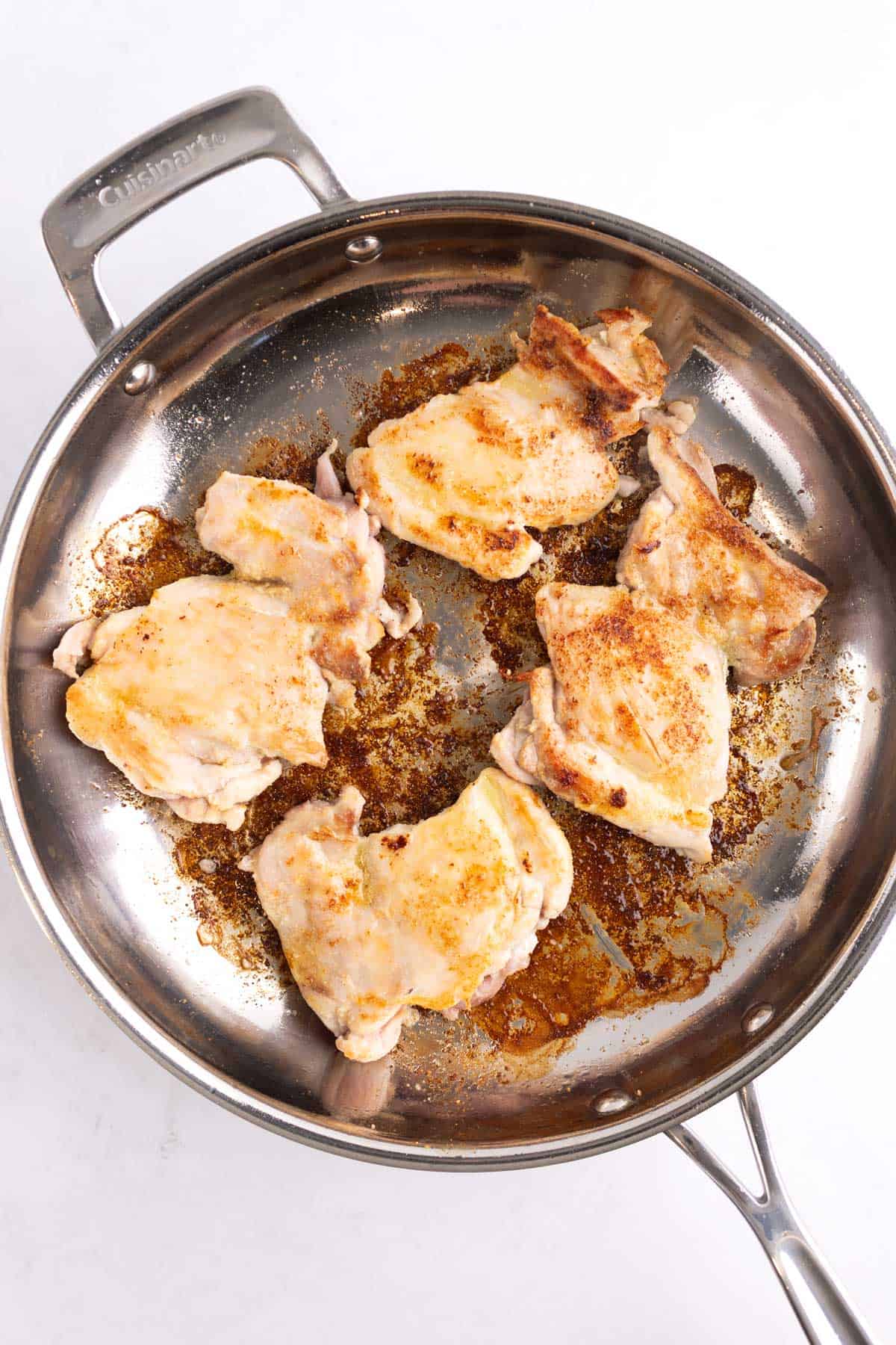 A skillet with cooked chicken thighs.
