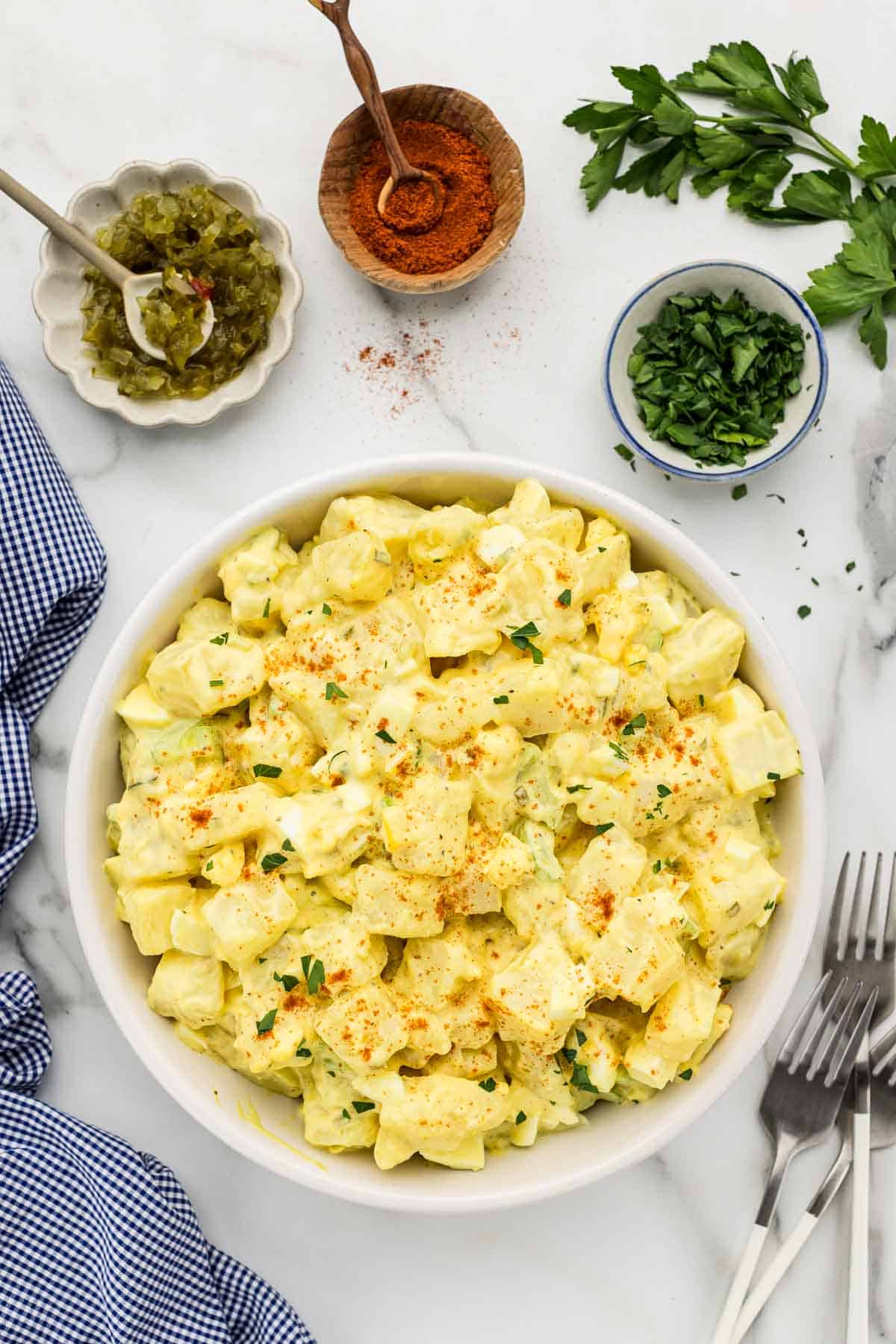 A serving of a potato salad with an array of ingredients arranged above it.