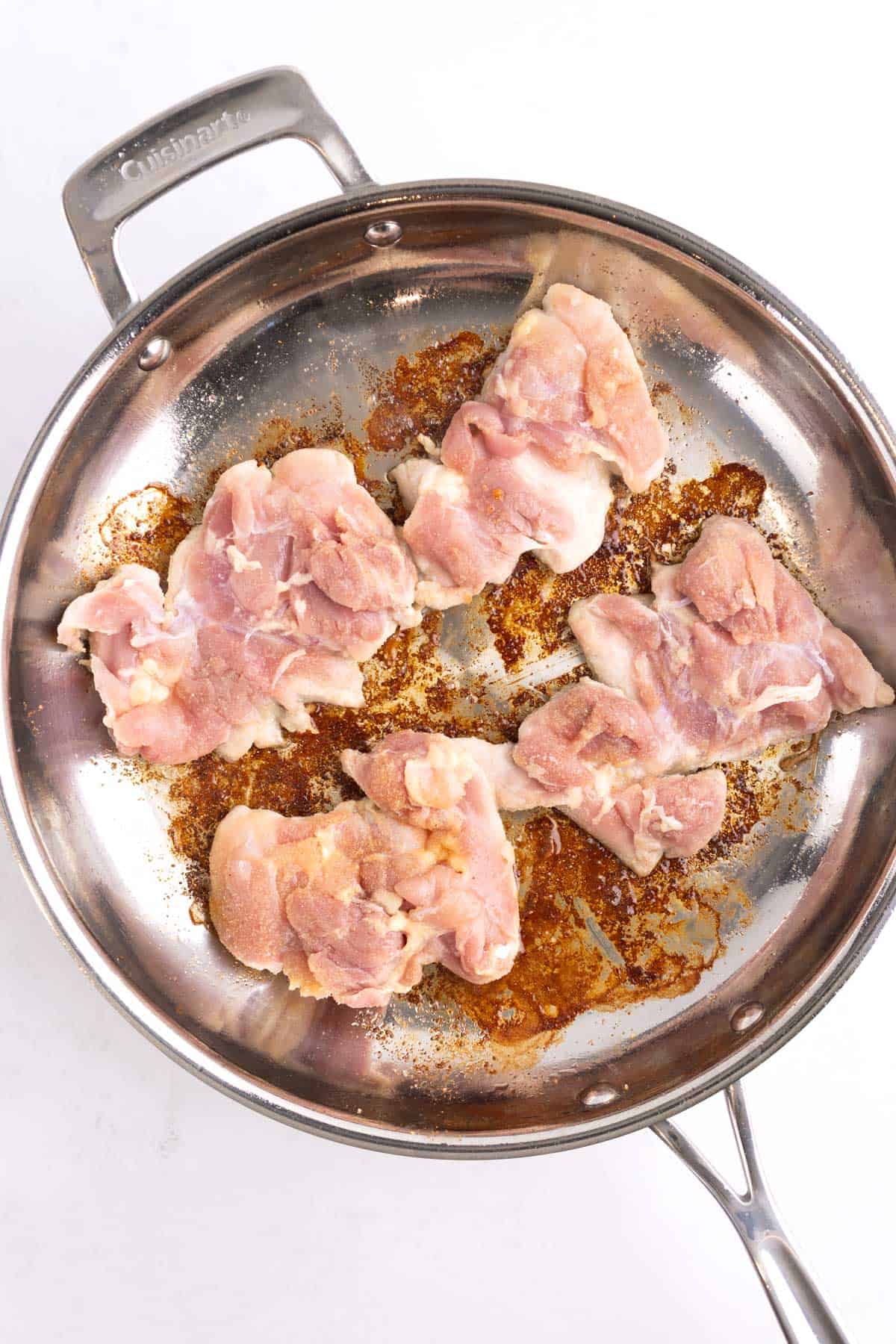 Raw chicken thighs set in a cooking pan.