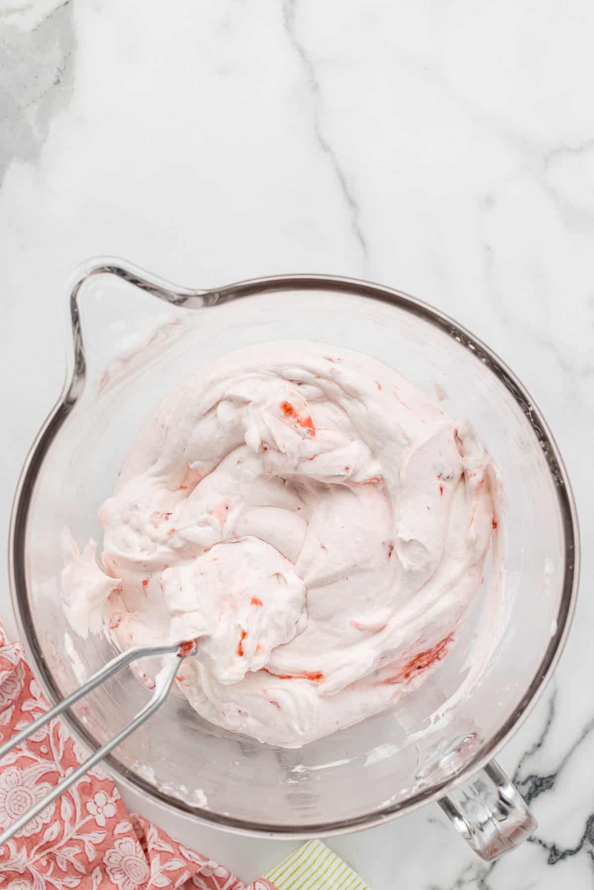 Creamy strawberry filling mixed in a large glass with a spatula.