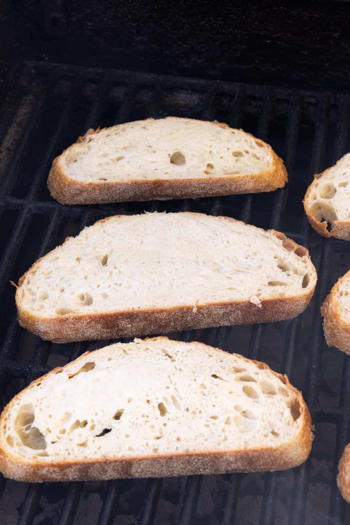 Bread slices sitting on the grill in rows.