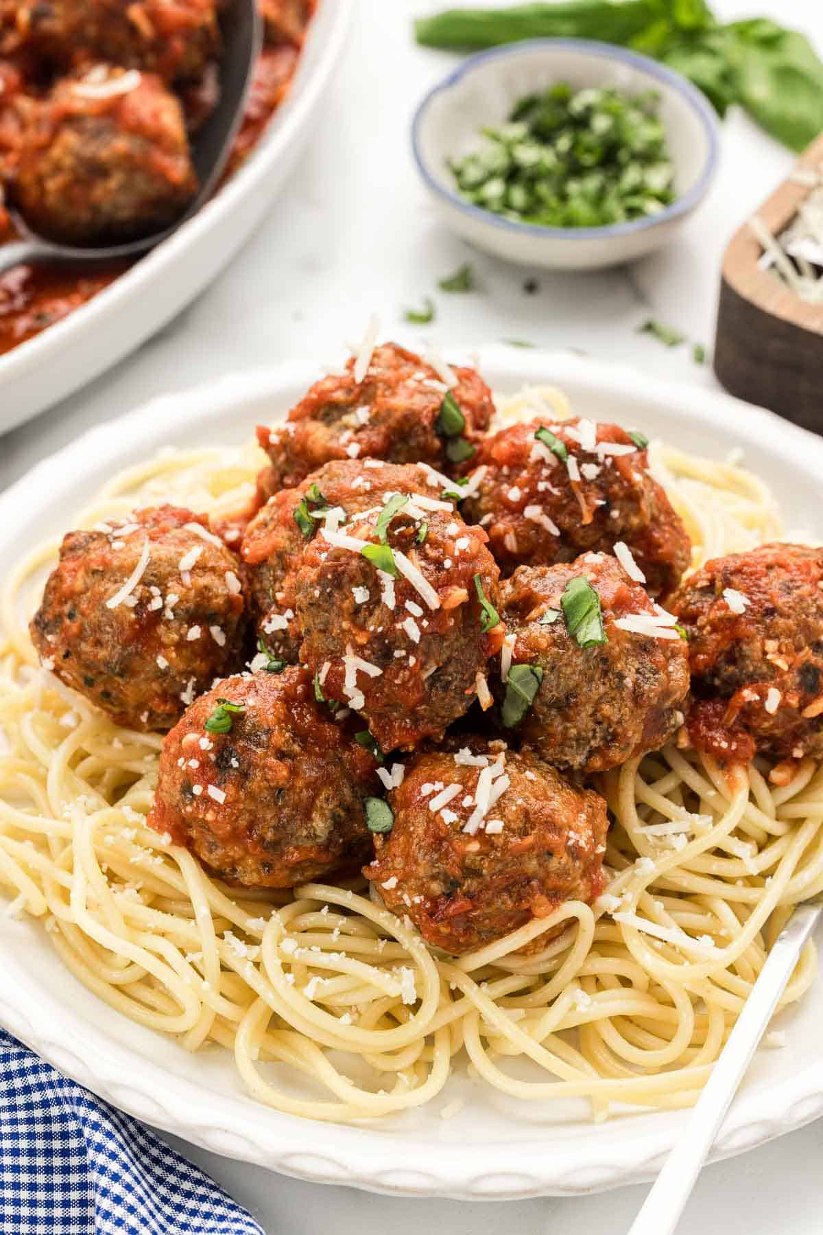 A pile of meatballs on a serving of noodles with a fork.