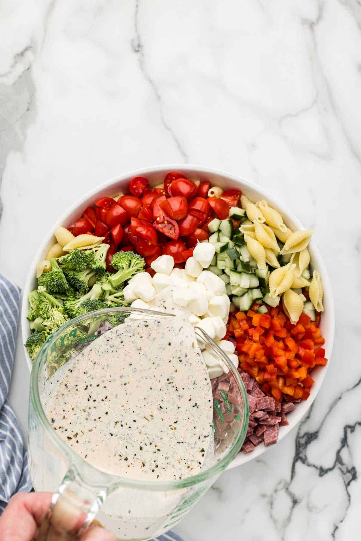 Dressing poured over pasta salad ingredients.