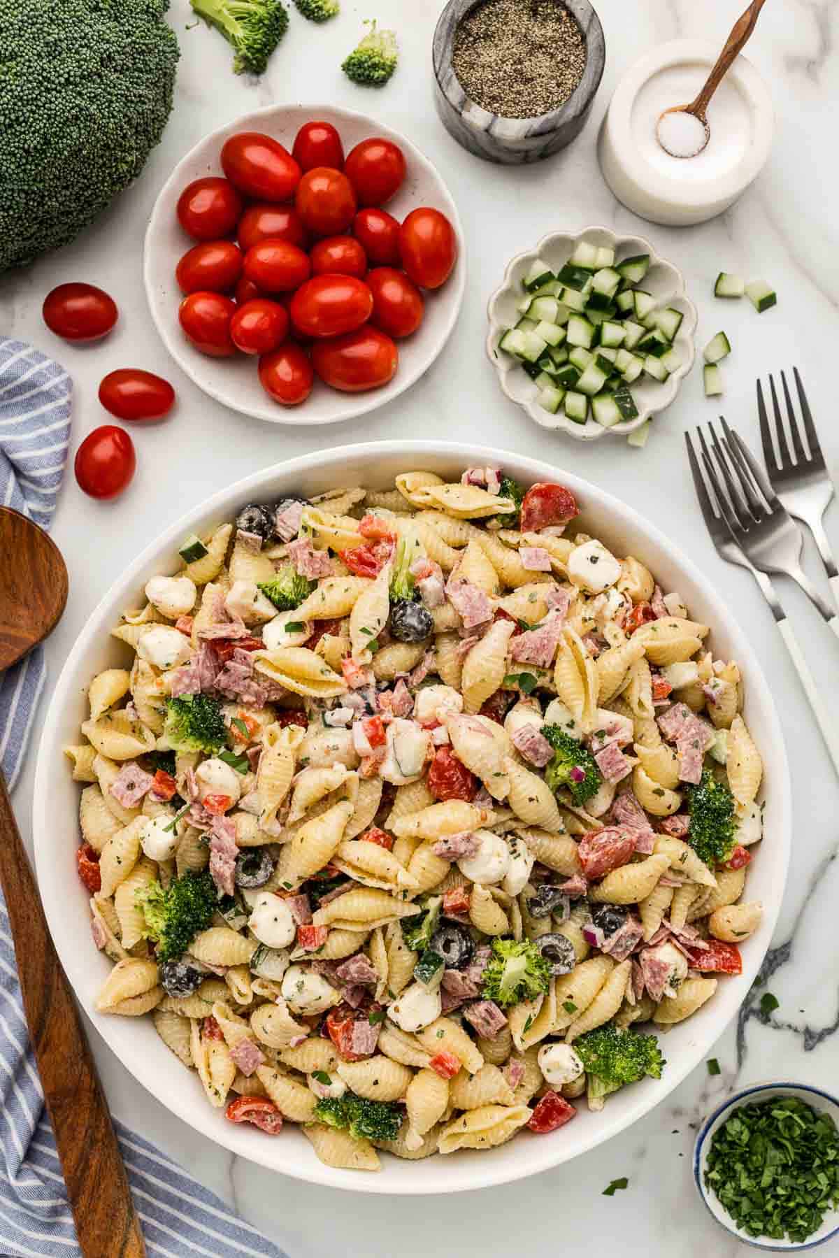 A large serving of pasta salad with creamy dressing in a glass white bowl.