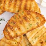 A pile of grilled bread pieces sprinkled with herbs.