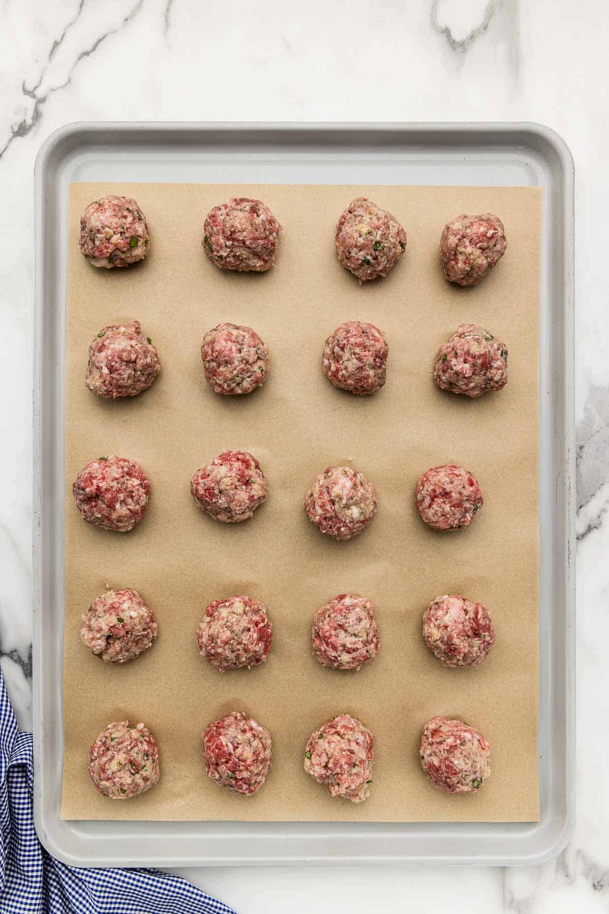 Raw meatballs on a sheet pan.