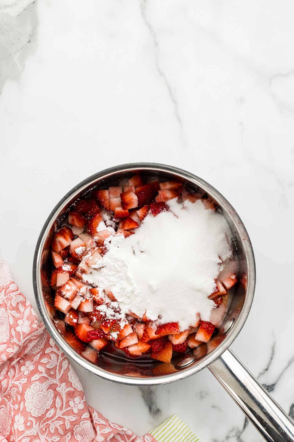 Strawberries and sugar in a saucepan.