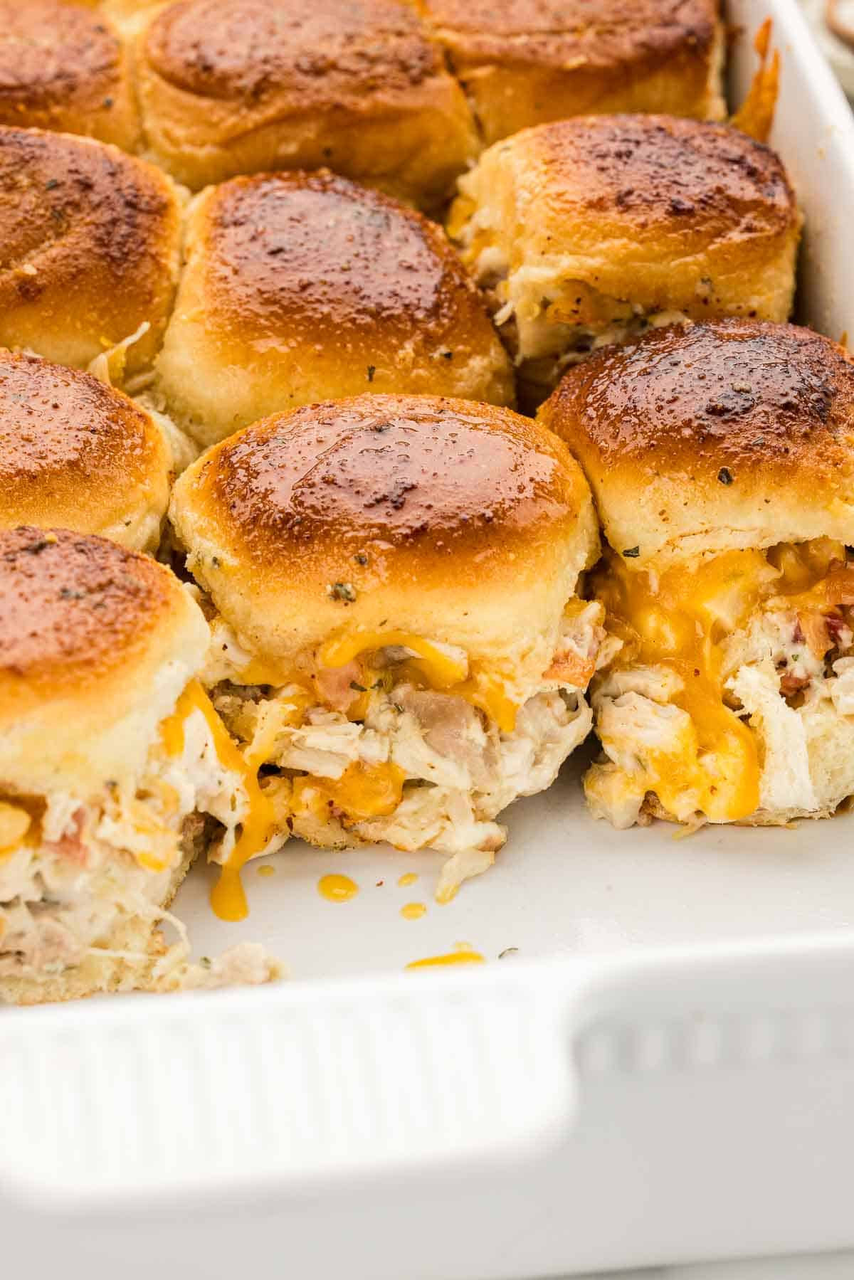 Closeup of a row of sliders in a white baking pan.
