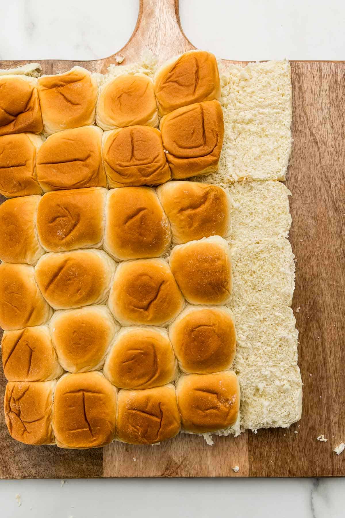 Buns sliced in half on a wooden cutting board.