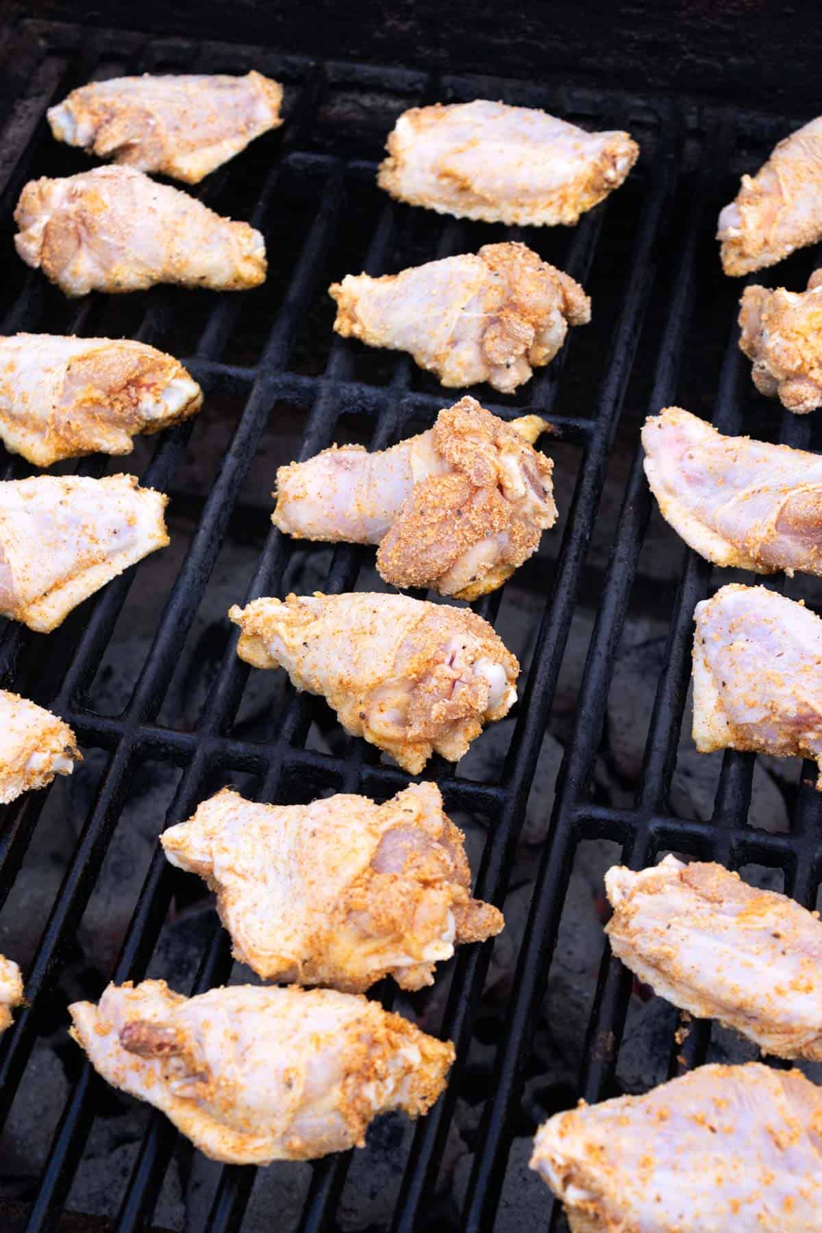 Raw wings covered in seasoning on a grill.
