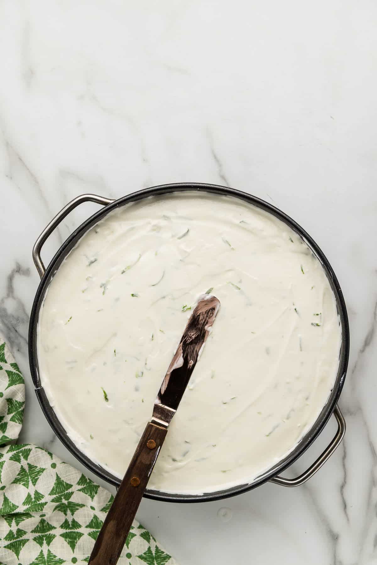 Smoothing the top of a cheesecake with a spatula.