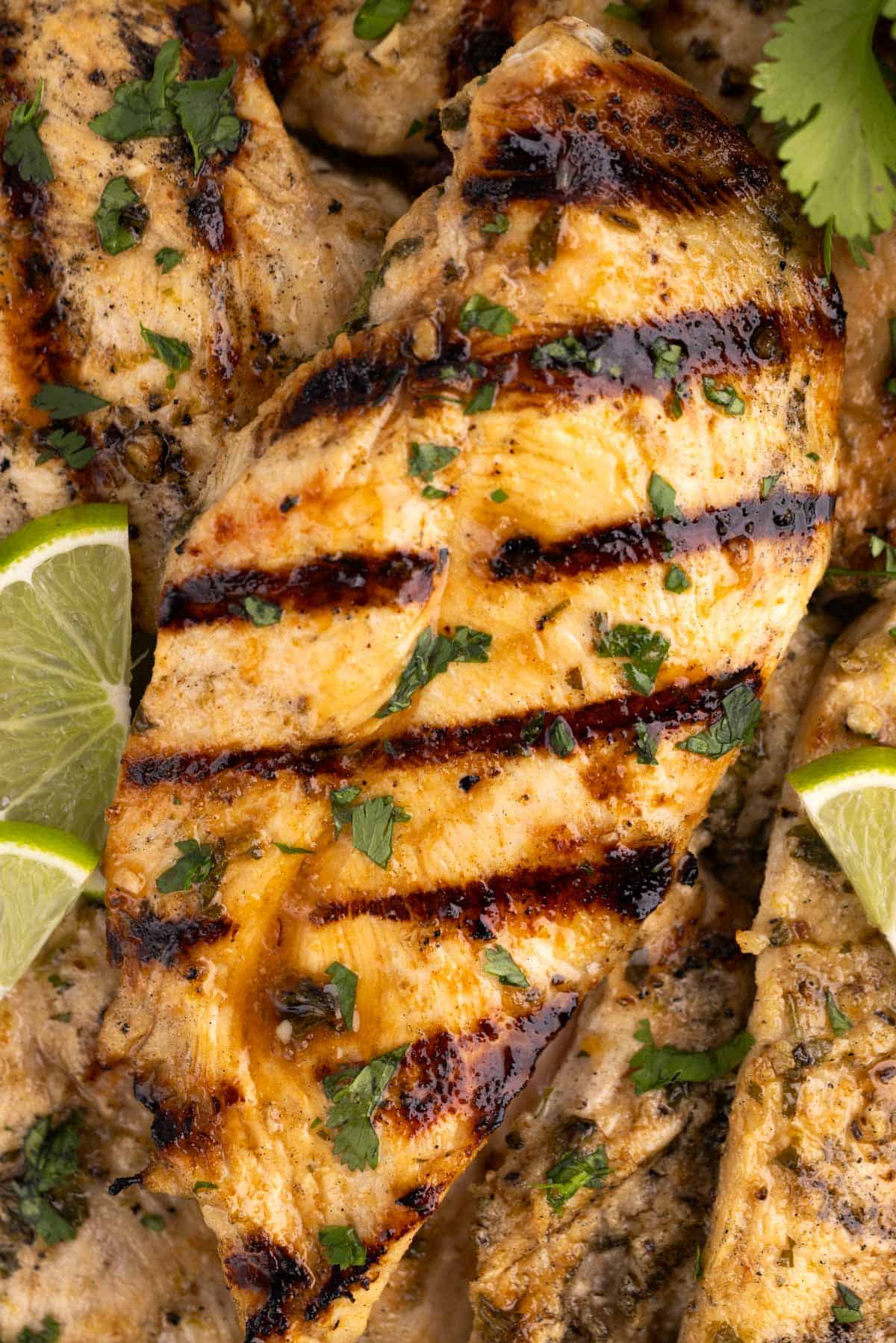 Closeup of a grilled chicken breast with lime slices.