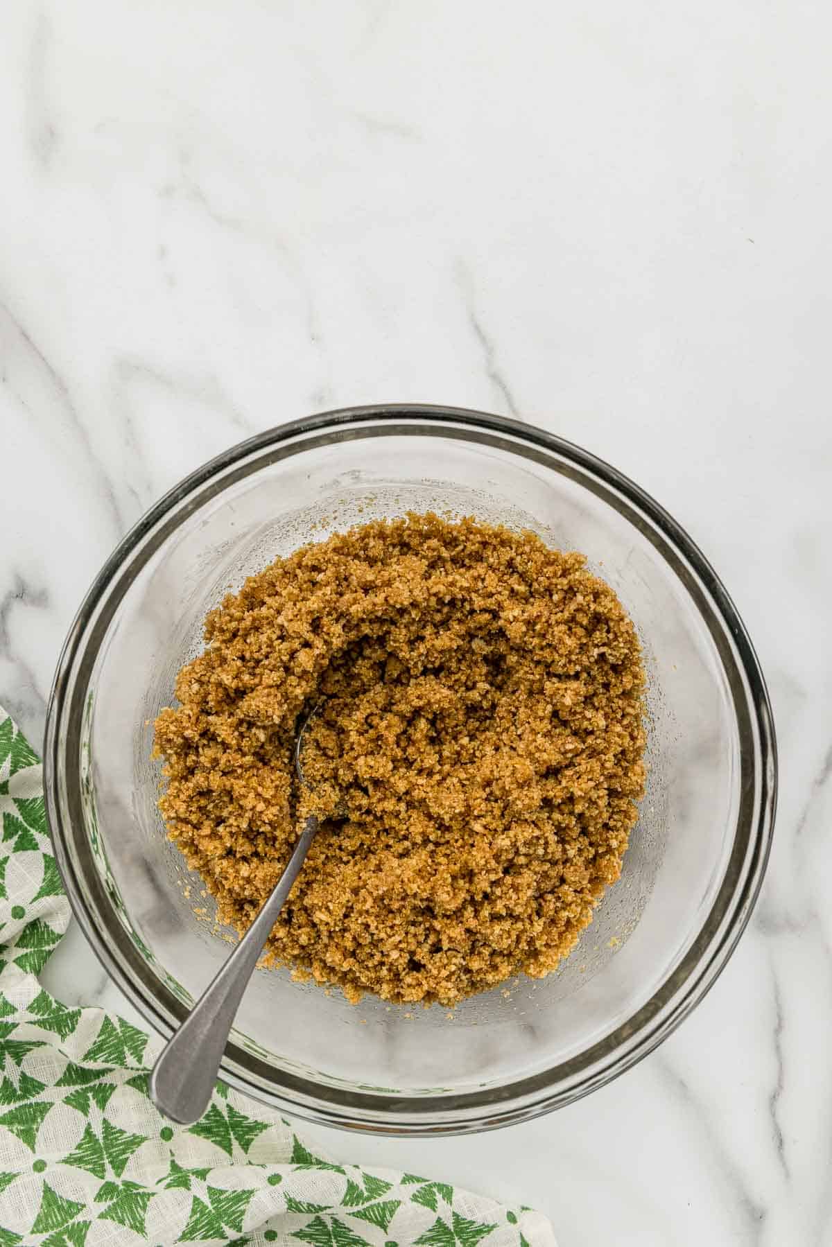 Graham cracker crust mixed in a small bowl with a spoon.