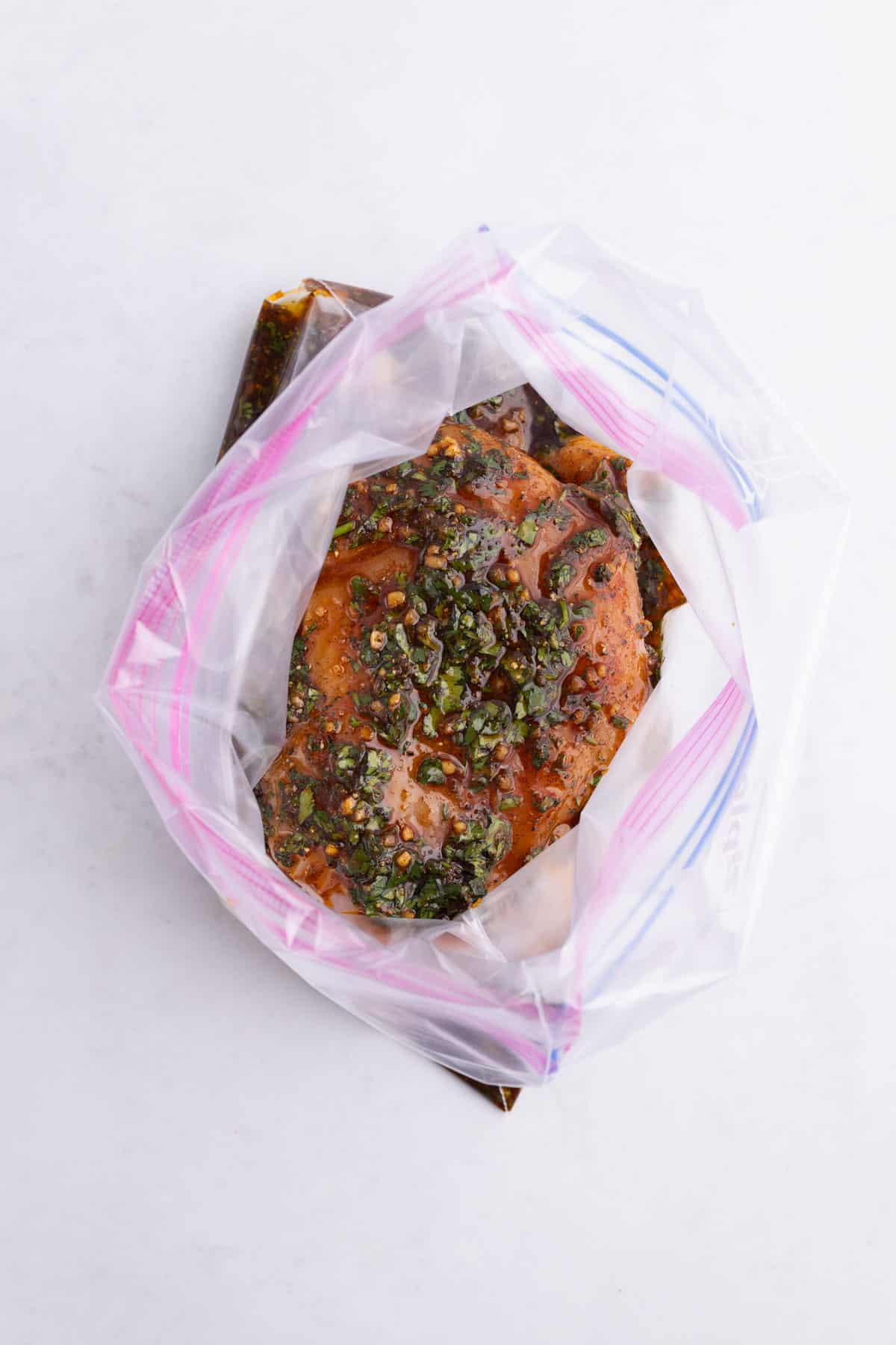A ziplock bag full of raw chicken sitting in a chili lime marinade.
