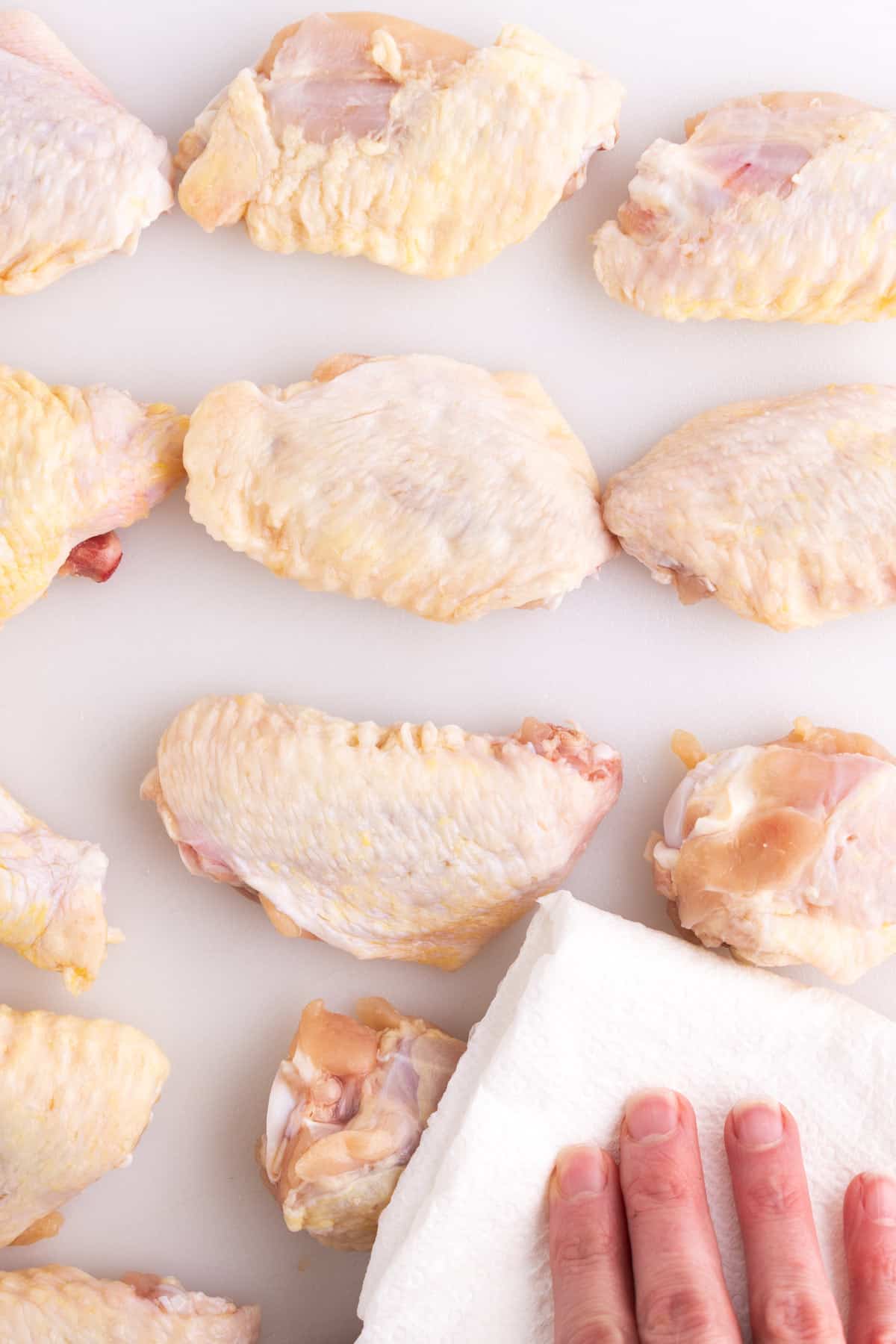 Raw wings getting pat dry with a paper towel.