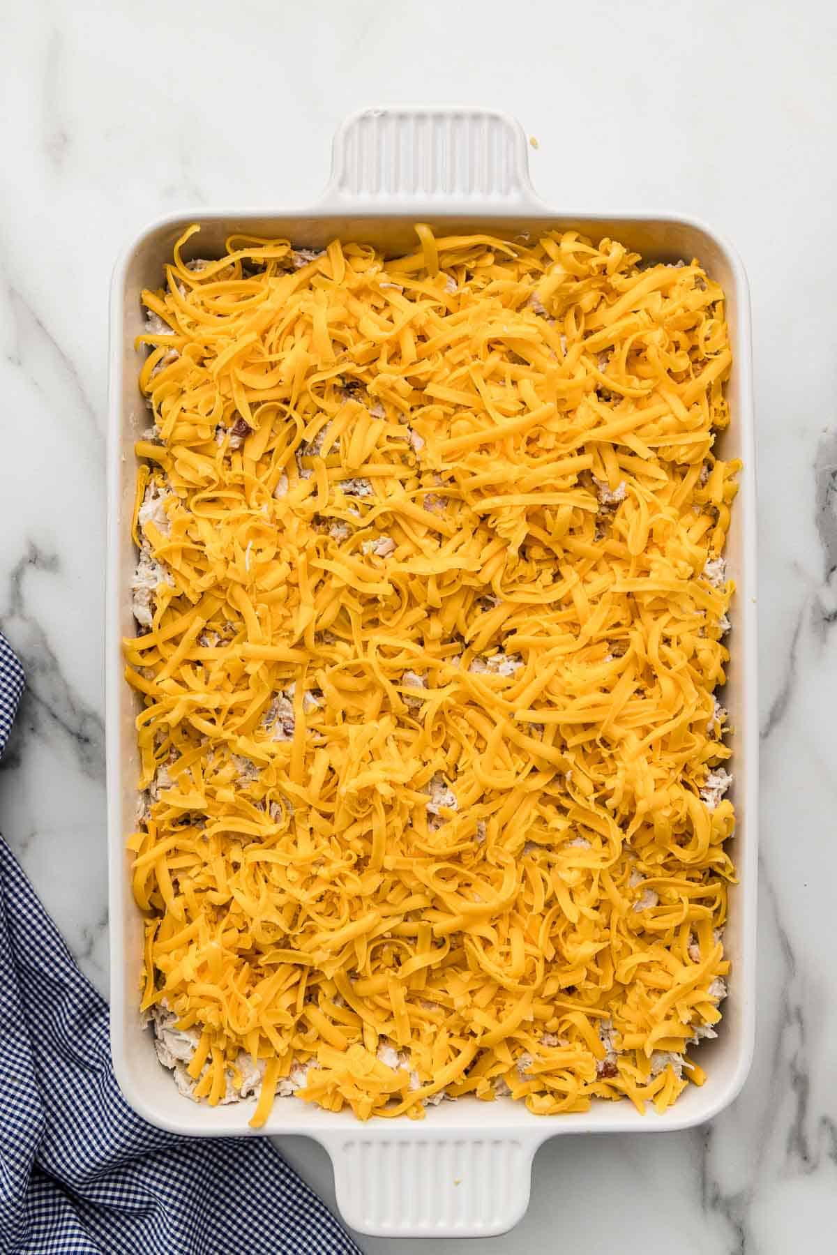 Shredded cheese piled onto a pan full of sliders.