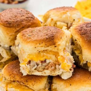 A chicken bacon ranch slider sitting on top of a pile of sliders with melted cheese.