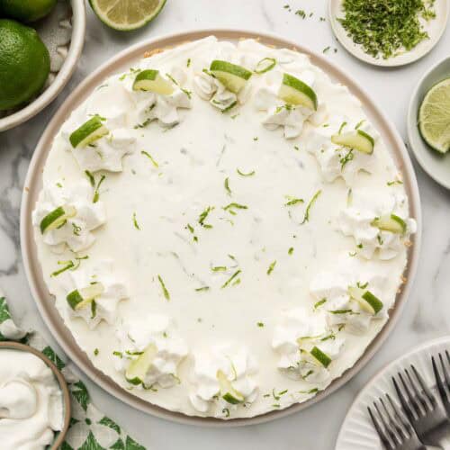 A whole key lime cheesecake topped with lime slices and whipped cream.