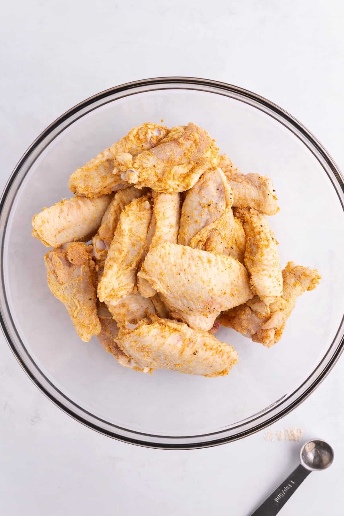 A large bowl of wings covered in seasoning.