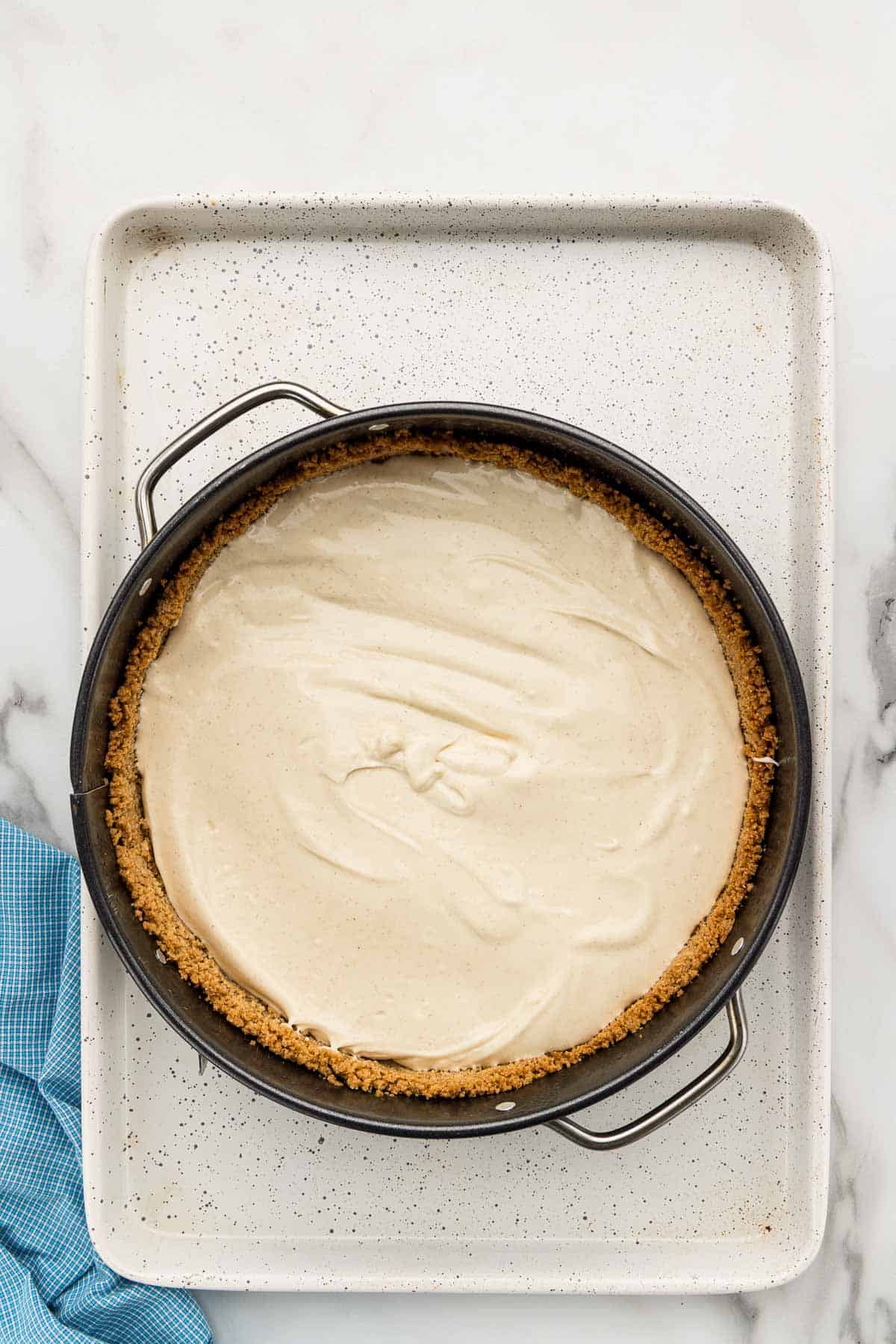 Batter and crust in a springform pan on a baking sheet.