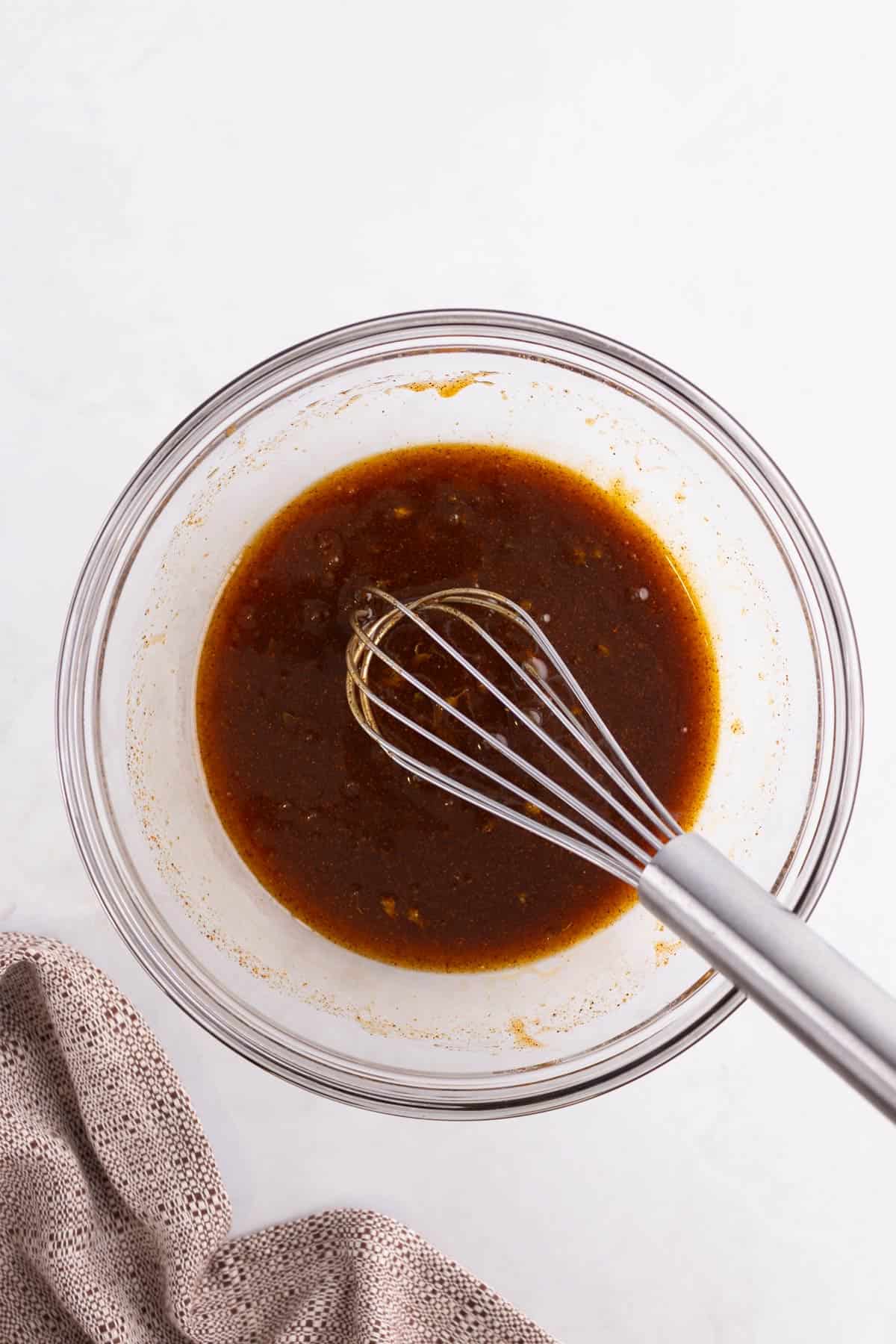 Honey chipotle sauce in a glass mixing bowl with a whisk.