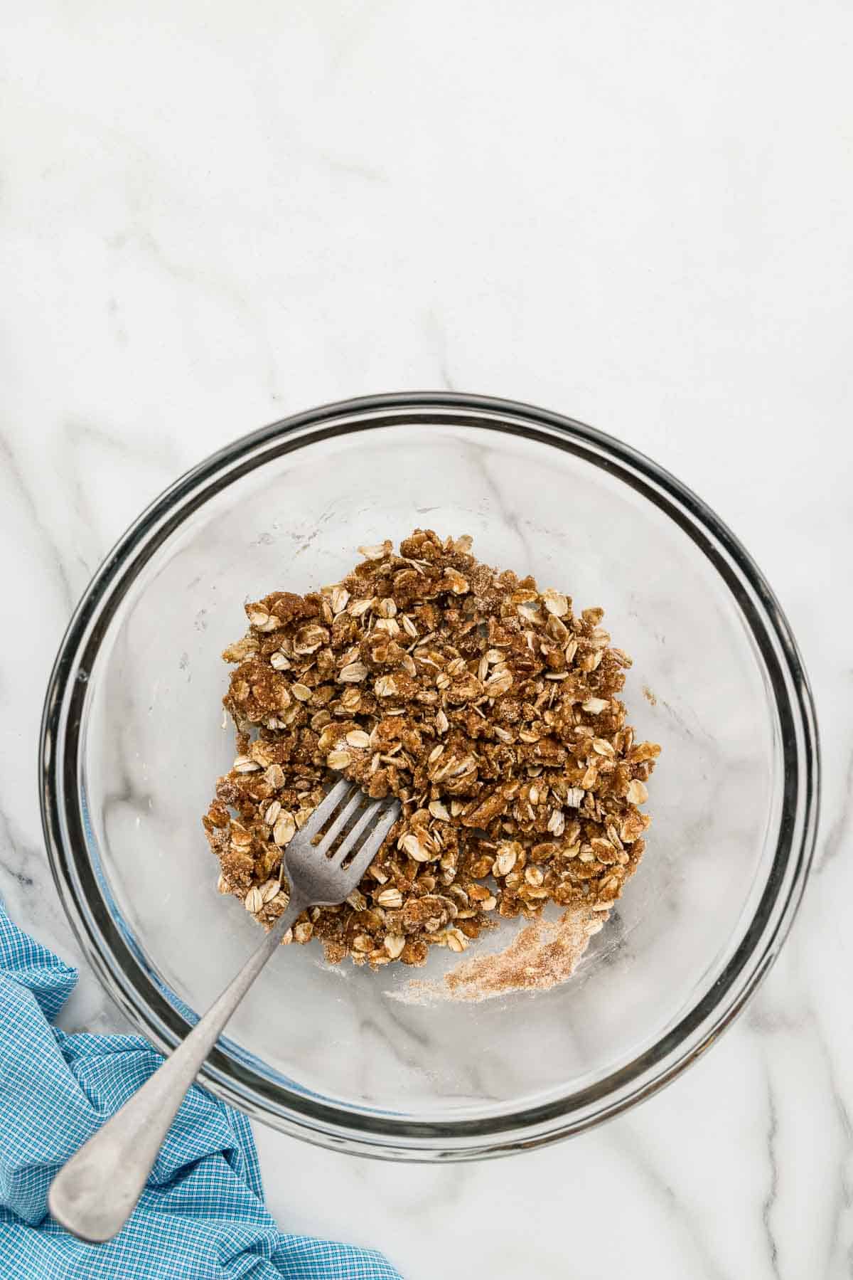 Crumble topping mixed in a glass bowl with a fork.