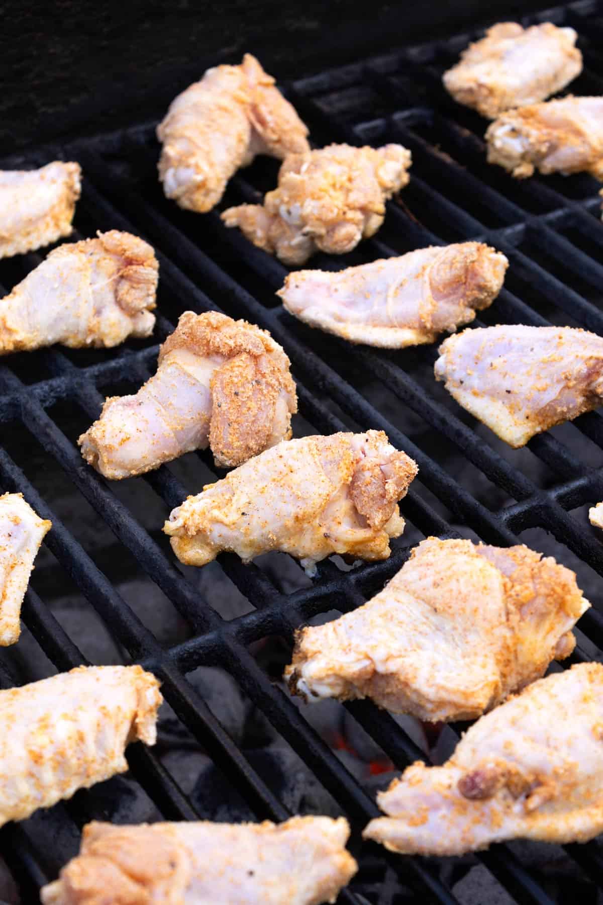 Raw wings sitting in rows on a grill.
