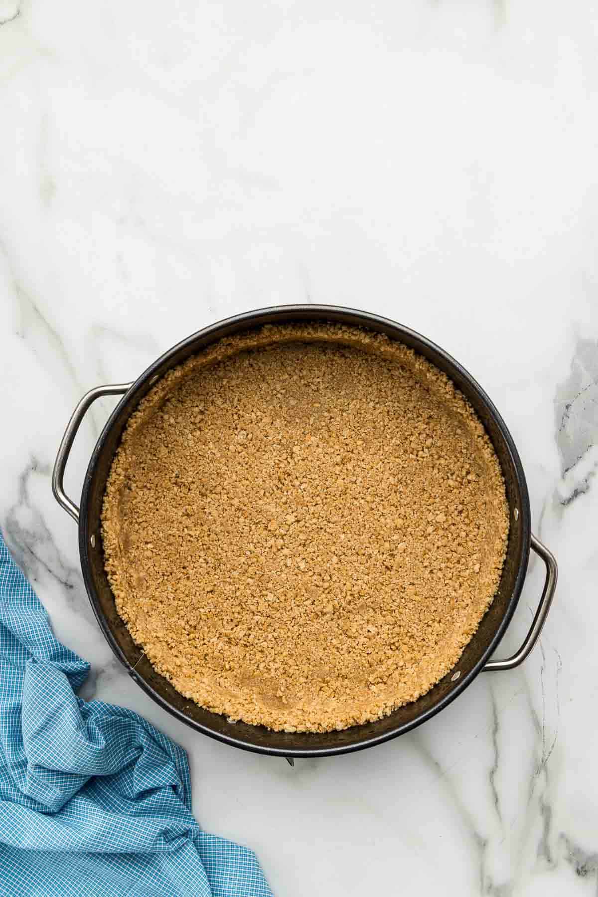 A graham cracker crust in the bottom of a round pan.