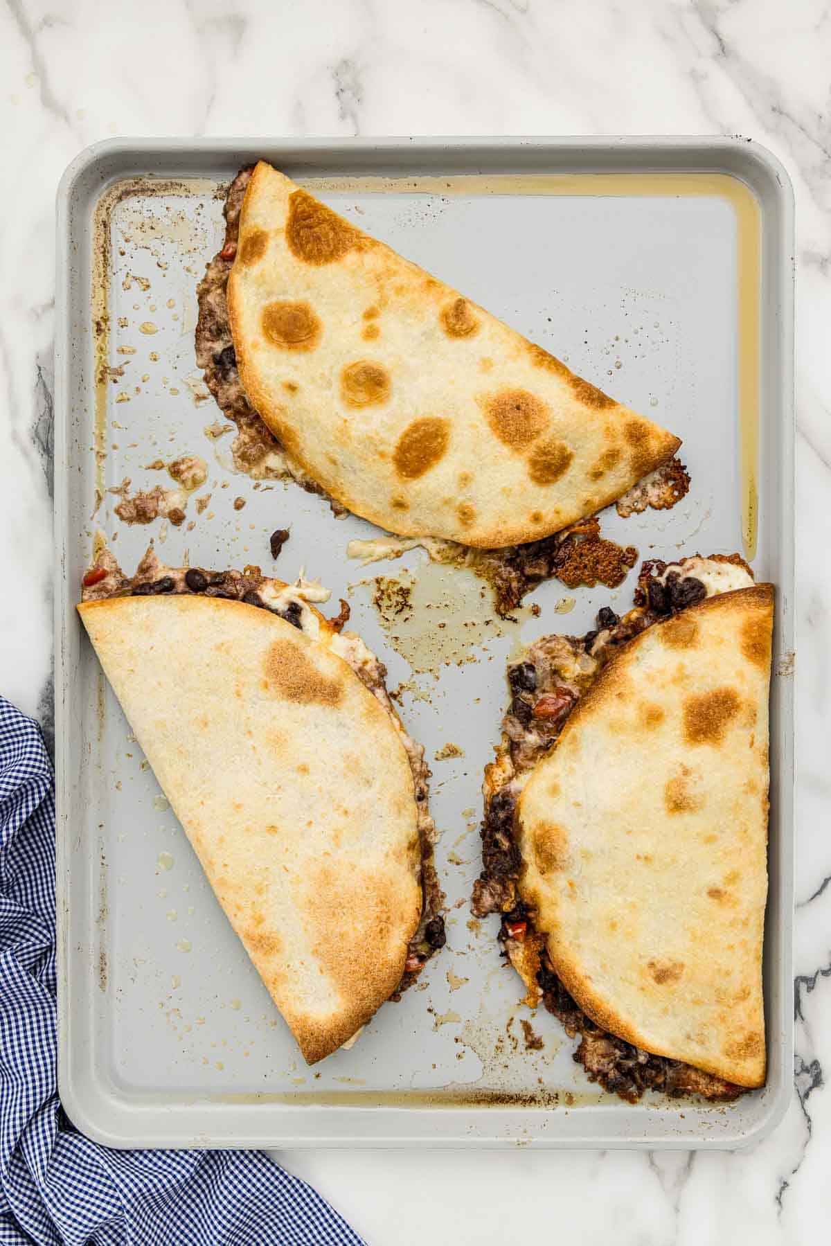 Baked quesadillas on a cookie sheet.
