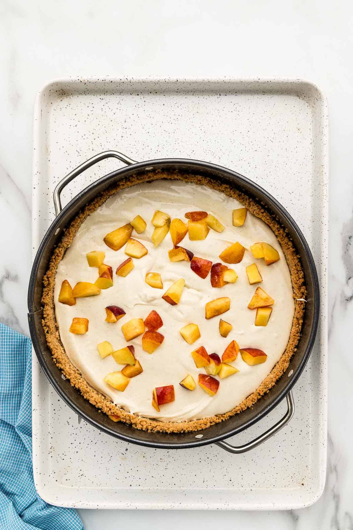 Cut peaches sprinkles over cheesecake filling in a round baking pan.