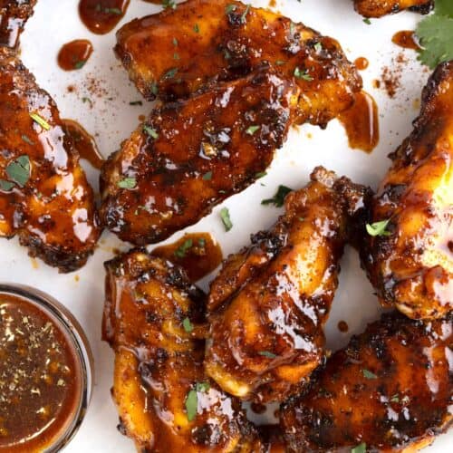 Honey chipotle wings in a pile with a small dish of sauce.