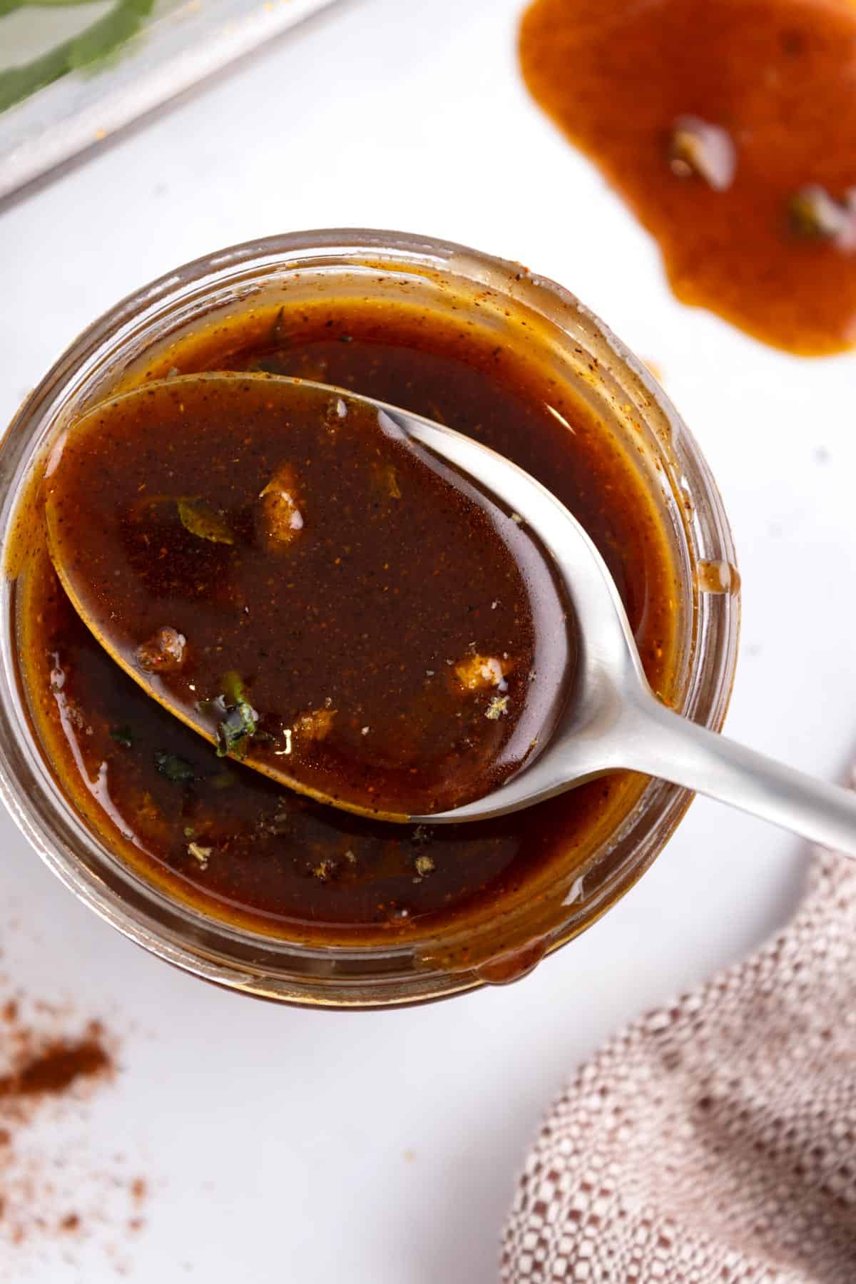 Overhead of a jar of honey chipotle sauce with a spoon scooping some out of the top.