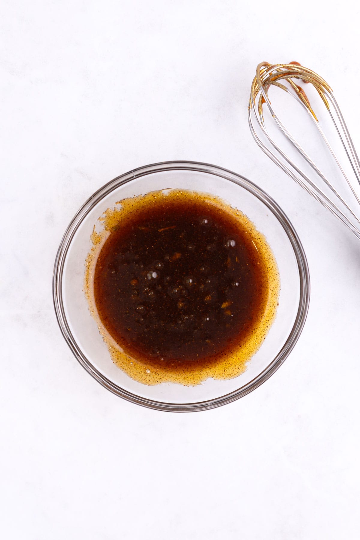 A small dish of honey chipotle sauce with a whisk.