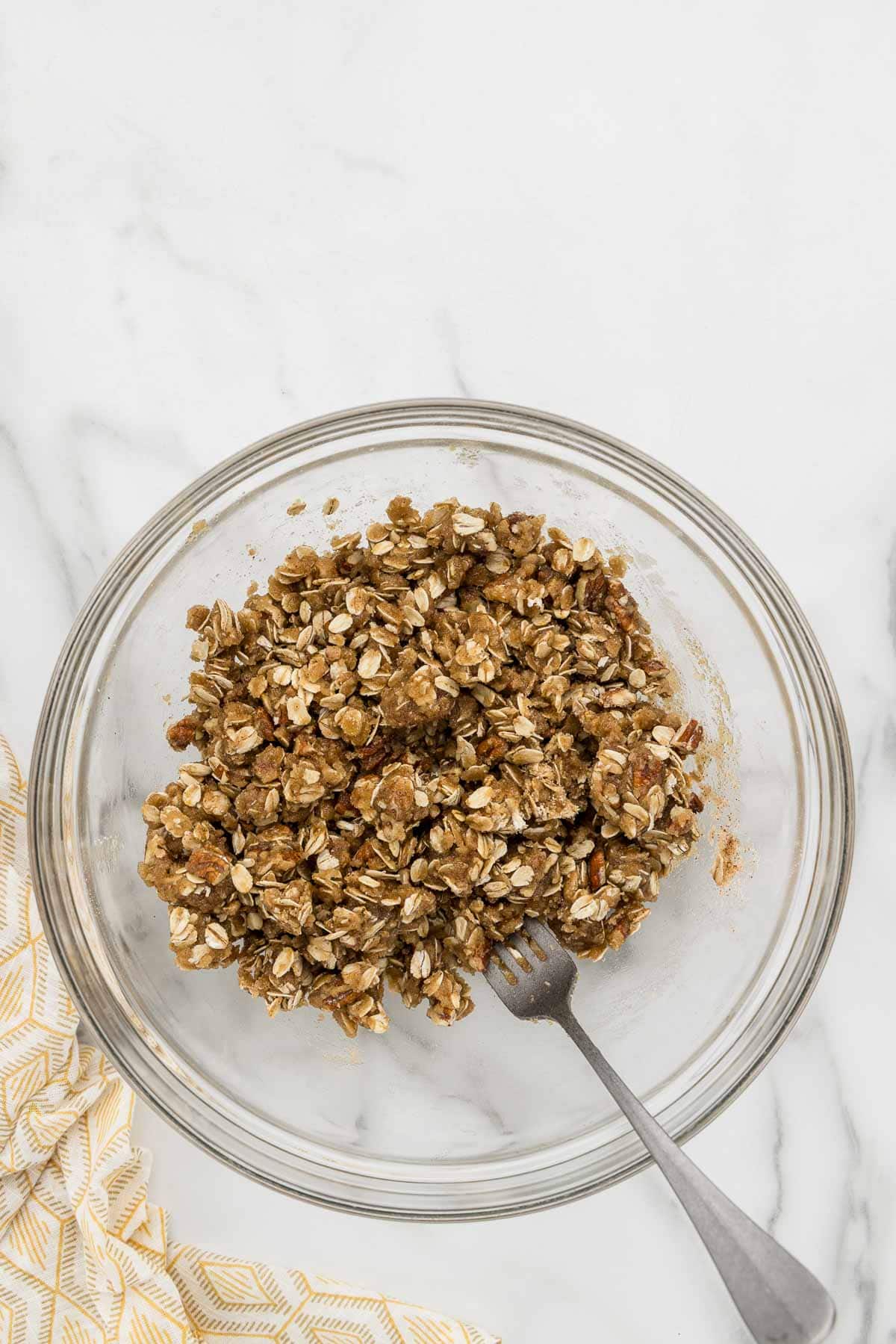 Oat crumble in a mixing bowl with a fork.