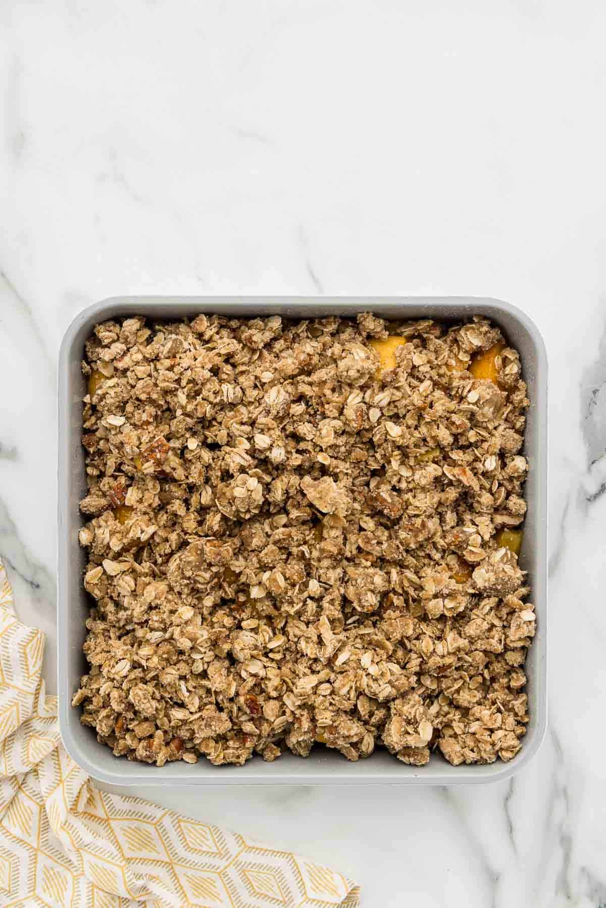Peach crumble with crispy topping in a baking pan.