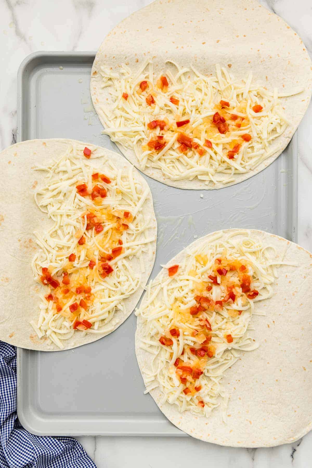 Tortillas with salsa and cheese on them.