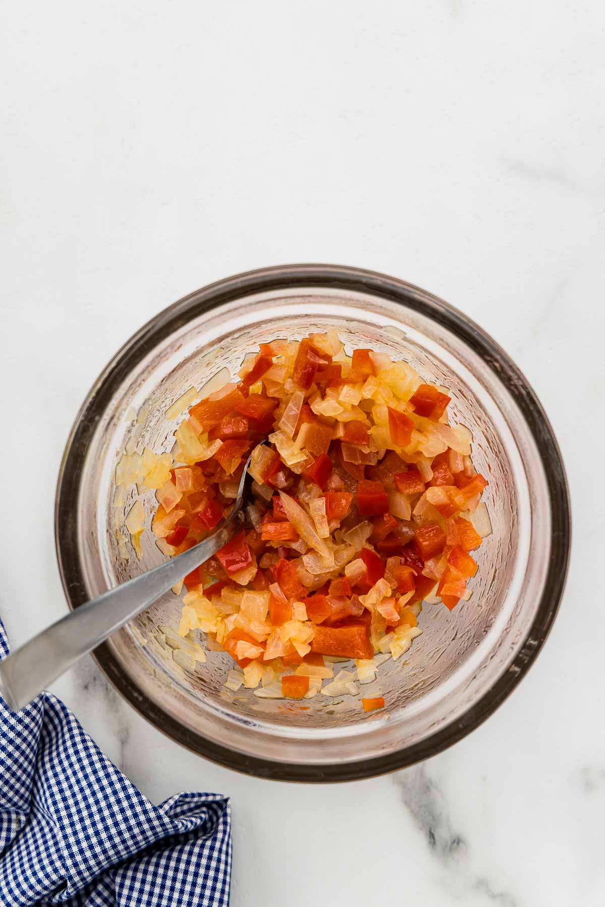 Chopped veggies stirred together in a jar with a spoon.