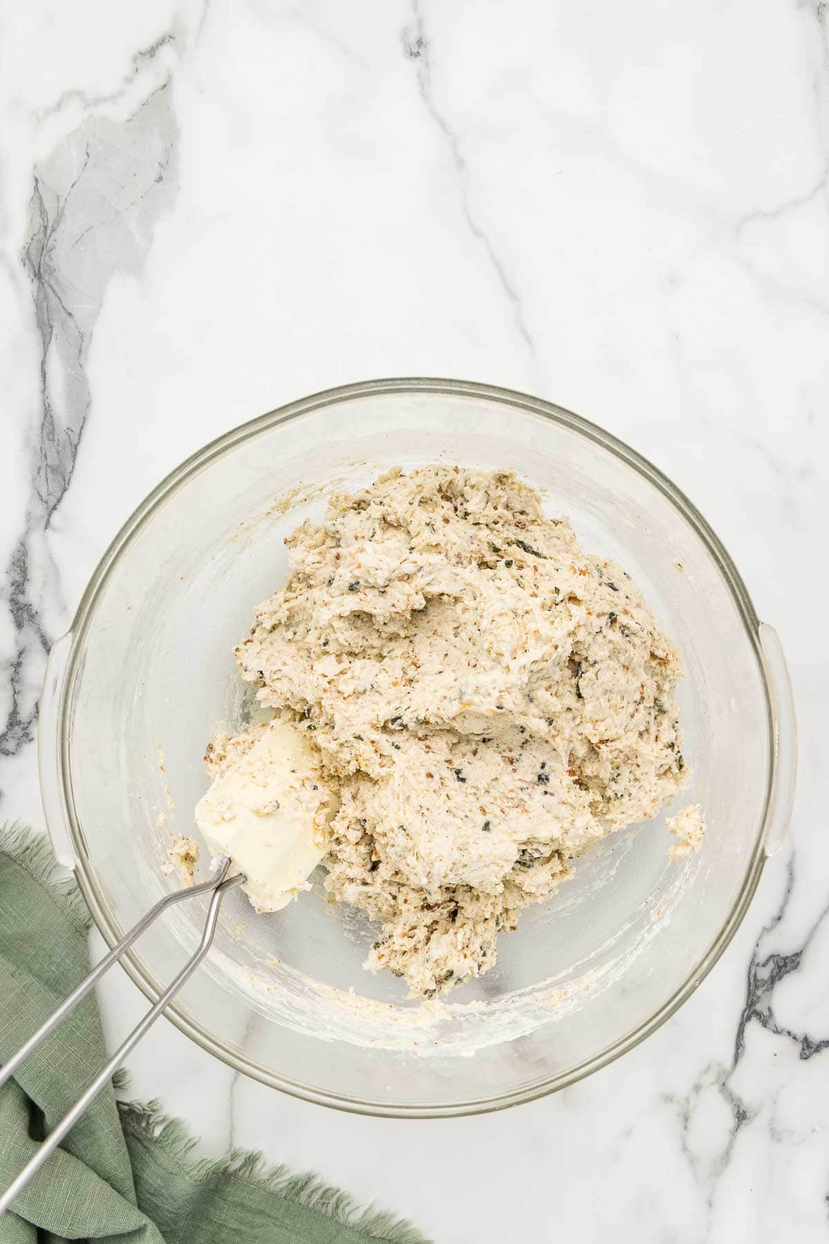 A glass mixing bowl of biscuit dough with a rubber spatula.