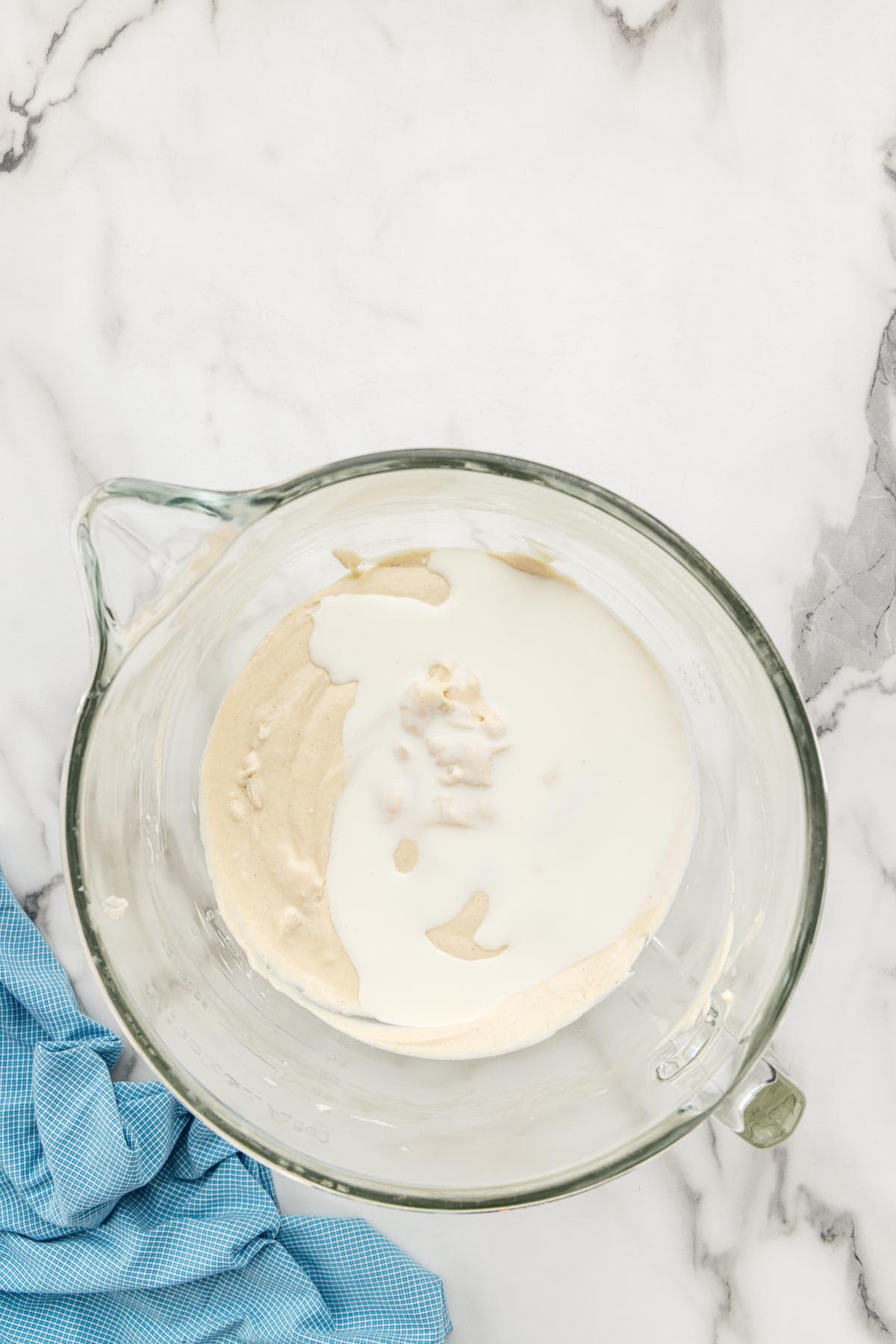 Heavy cream added to a glass cup of cheesecake batter.