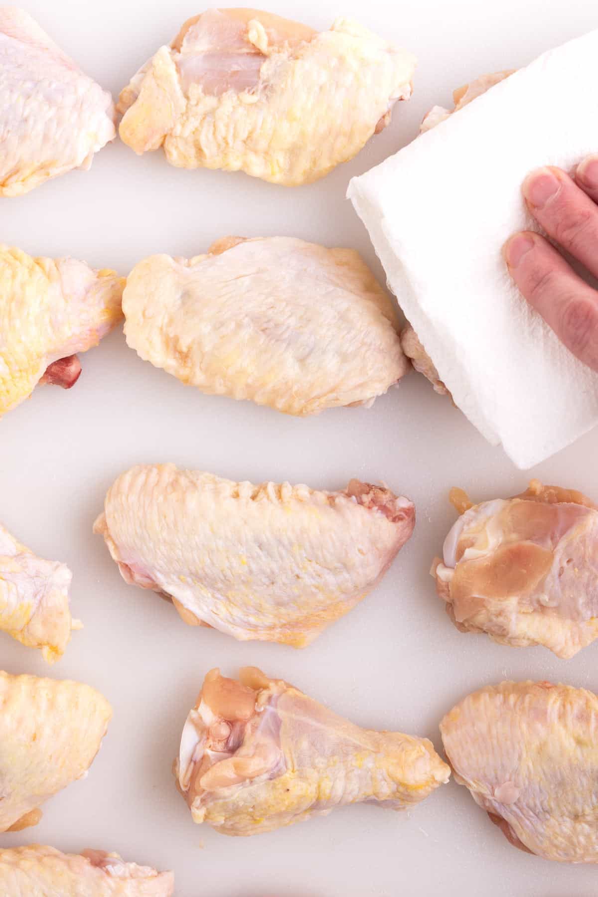 Raw chicken wings getting dried with a paper towel.