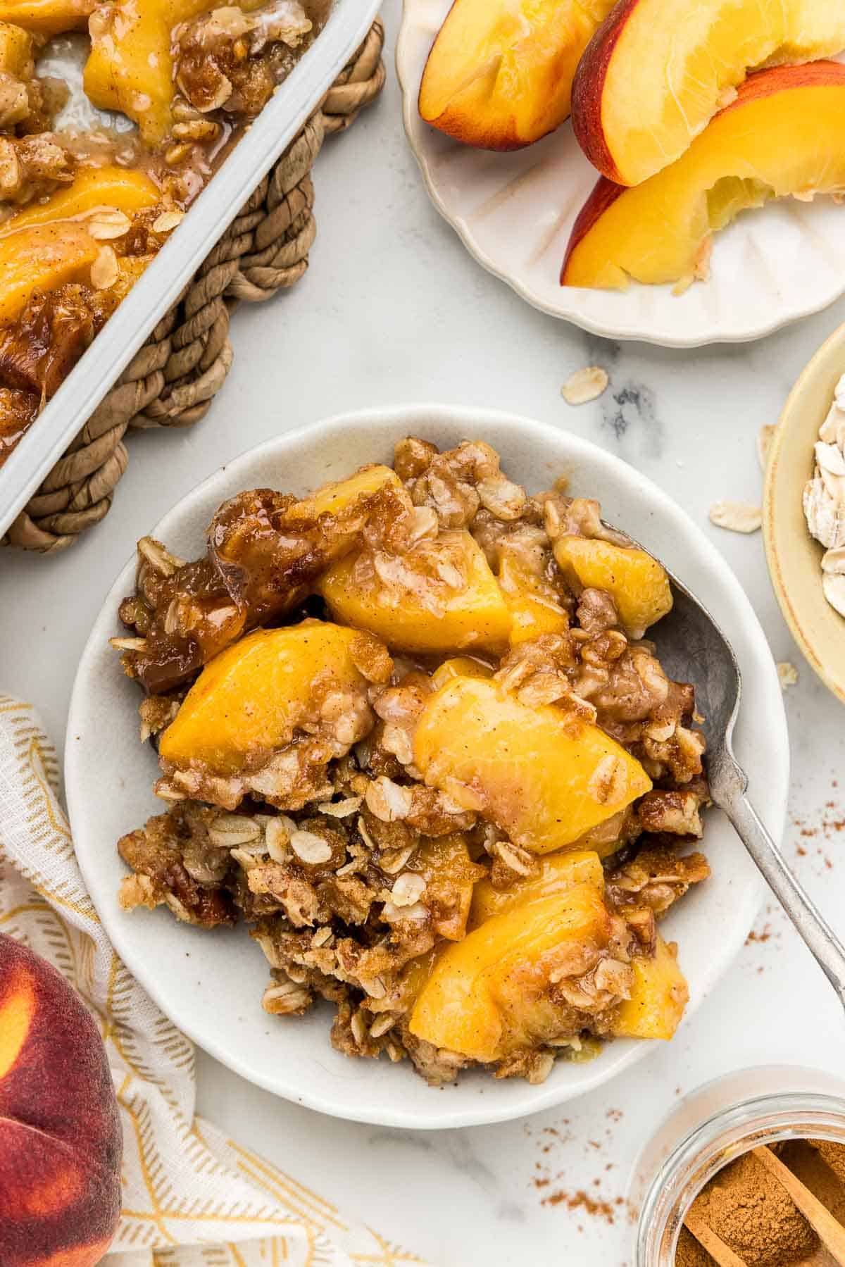 A serving of peach crumble with a spoon.