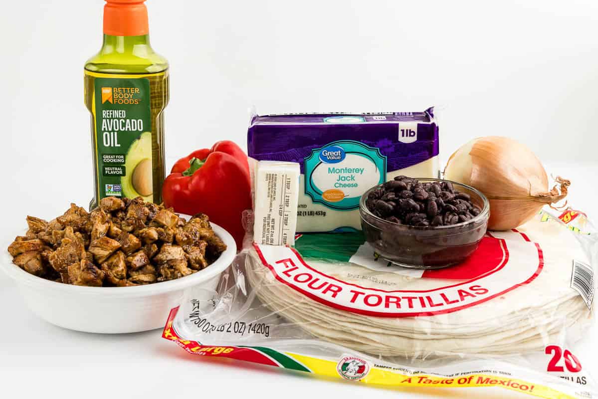 Chicken, oil, a bell pepper, cheese, butter, tortillas, beans, and onion on a white counter.